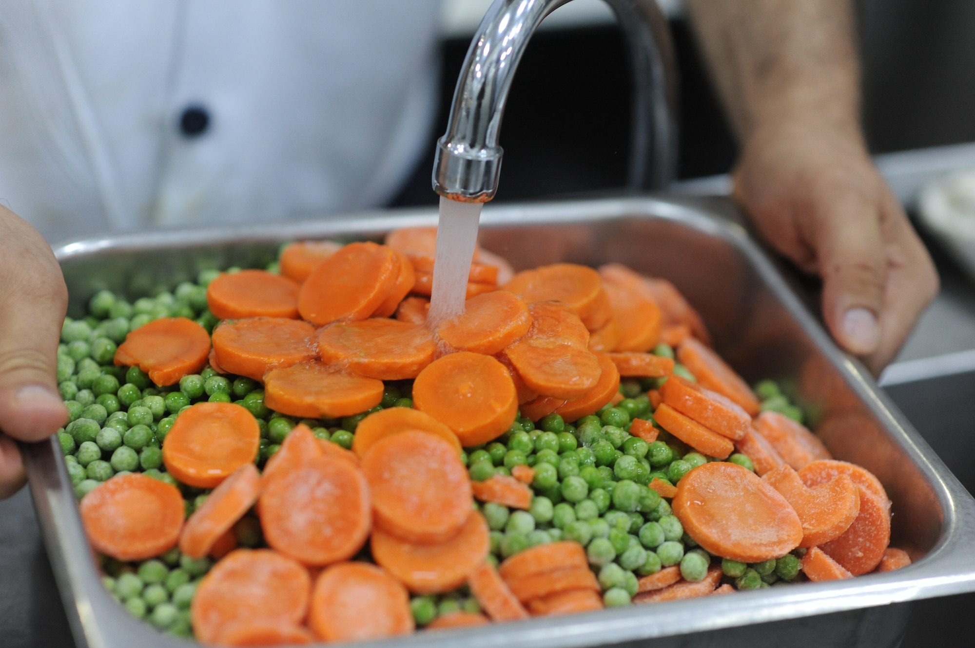 Frozen peas and carrots are rinsed off and prepared to be cooked July 27, 2012,  at the Sultan's Inn Dining Facility at Incirlik Air Base, Turkey. The Sultan's Inn offers breakfast, lunch dinner and early breakfast on weekends. (U.S. Air Force photo by Senior Airman William A. O'Brien/Released) 