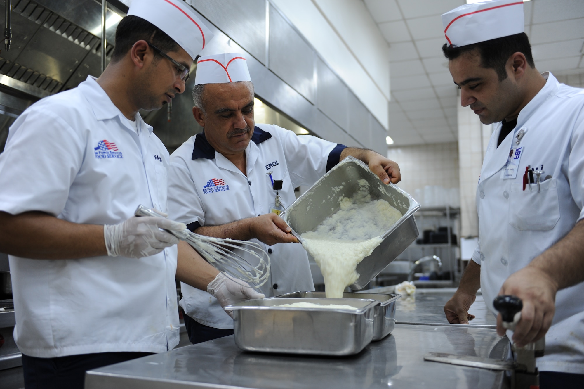 Harun Adiguzel, (left) 39th Force Support Squadron food services helper, Erol Kahveci (middle) 39th FSS cook and Ali Karsli 39th FSS senior cook, pour mashed potatoes while preparing lunch July 27, 2012 at the  Sultan's Inn Dining Facility at Incirlik Air Base, Turkey. The facility offers a main line a short order line and a variety of made-to-order foods such as sandwiches and chicken at lunch.(U.S. Air Force photo by Senior Airman William A. O'Brien/Released) 