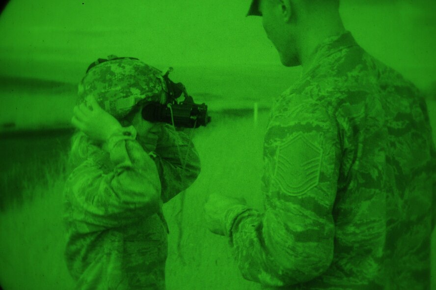 Master Sgt. Timothy Sullivan, 193rd Special Operations Security Forces Squadron, helps Senior Airman Kimberly Galutia, 201st Red Horse Squadron, with her night vision goggle. Airman Galutia trained with the 193rd SOSFS in June during their annual training held at Fort Indiantown Gap, Annville, Pa. (Photo by: Air National Guard Photographer, TSgt Culeen Shaffer)