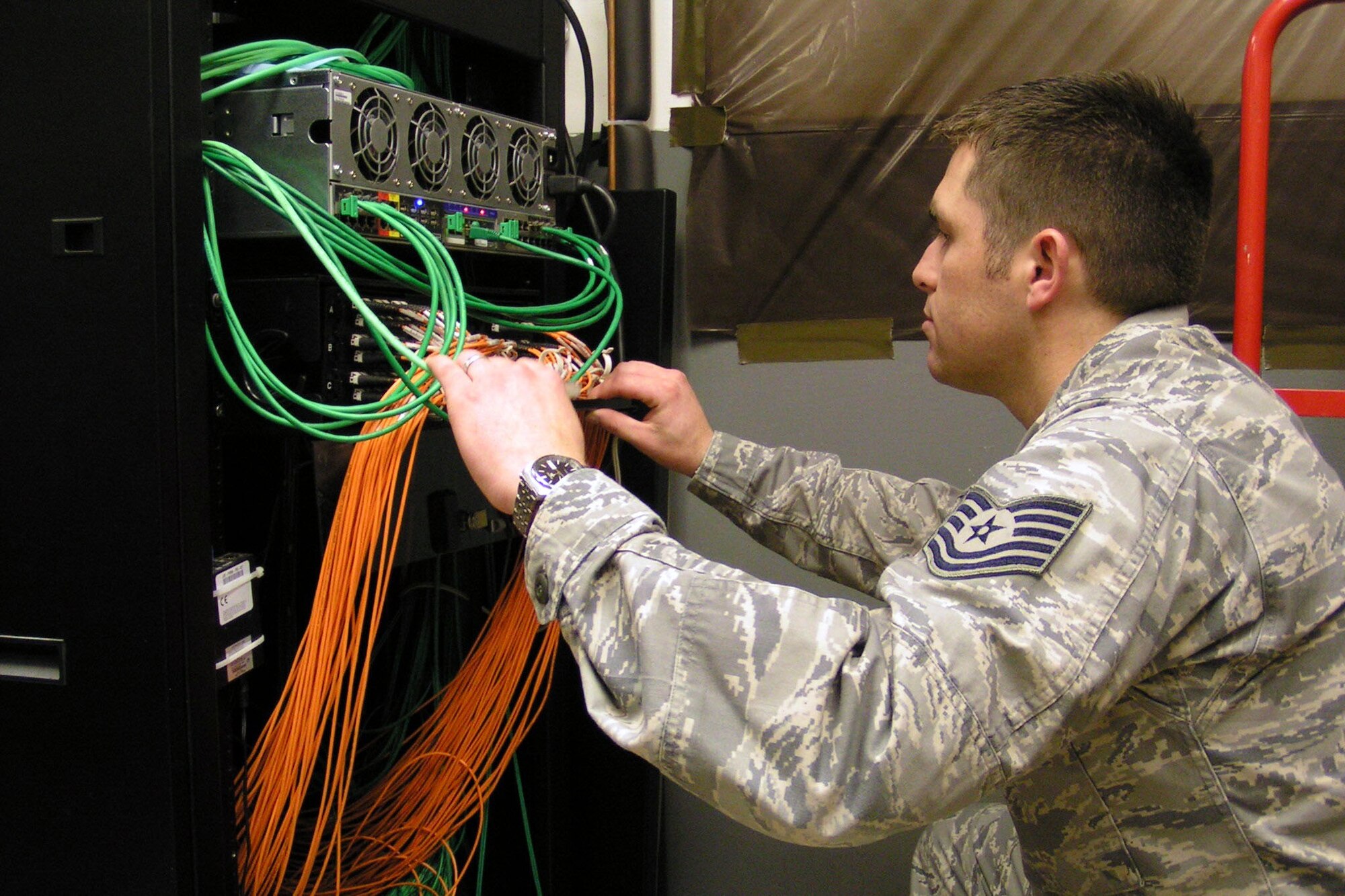 Tech. Sgt. Ryan Barkman, 611th Air Communications Squadron, performs a systems check on a rack-mounted server at Joint Base-Elmendorf-Richardson, Alaska, in a file photo. The Air Force Life Cycle Management Center Cyber Infrastructure Division at Hanscom AFB, Mass., has been working to consolidate four data processing centers into one area processing center to improve reliability of core services and reduce costs.  (U.S. Air Force photo)