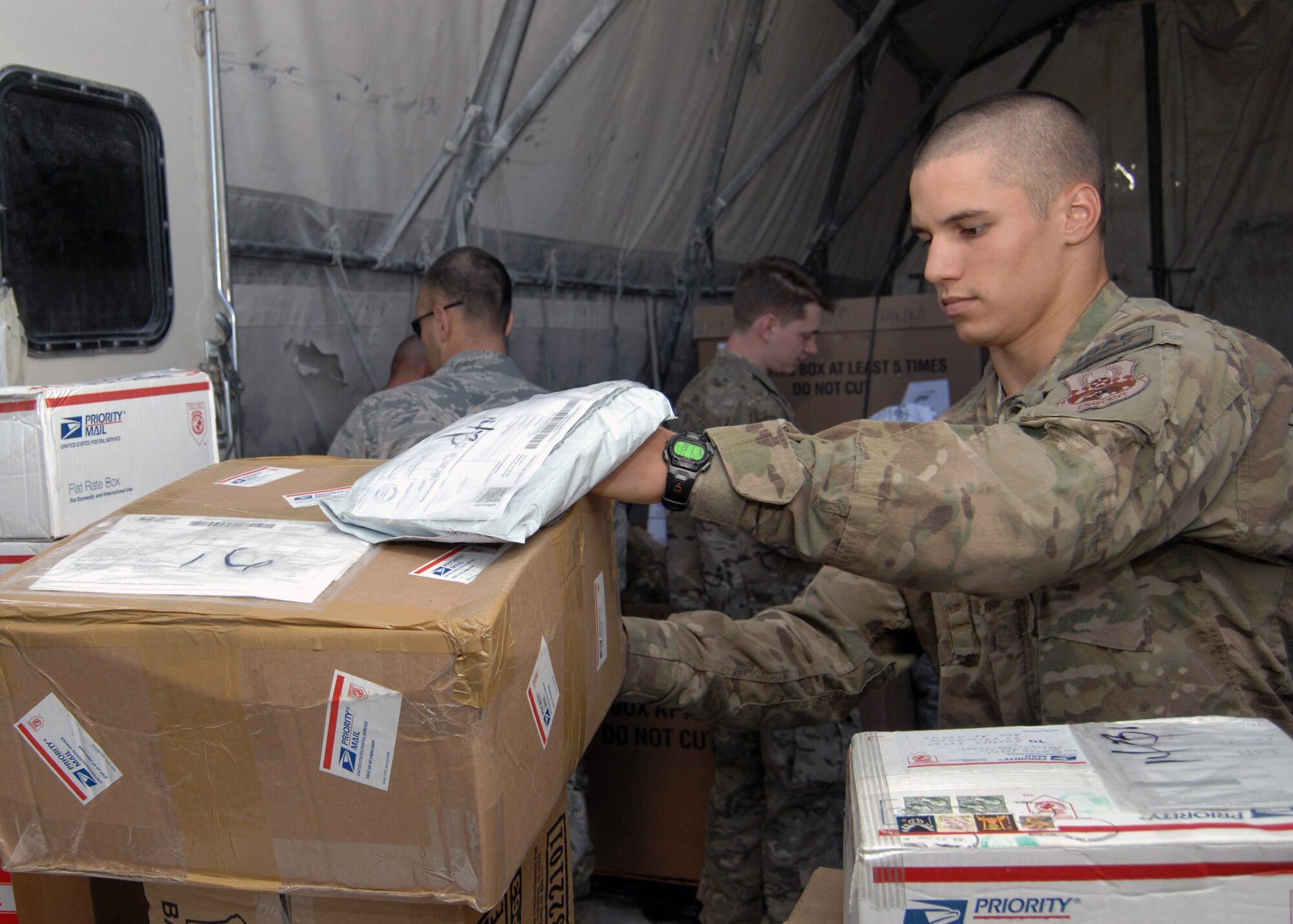 U.S. Air Force Senior Airman Matthew Holloway, 451 Expeditionary Logistics Readiness Squadron mail augmentee, helps load packages during the daily mail run. Typically, the mail run is accomplished at 7 a.m. Monday - Friday and augmentees from the various expeditionary groups are assigned to help load, and sort mail. Depending on the day, there can be between six and 22 pallets of mail to be loaded. (U.S. Air Force photo/Master Sgt. Russell Martin/RELEASED)