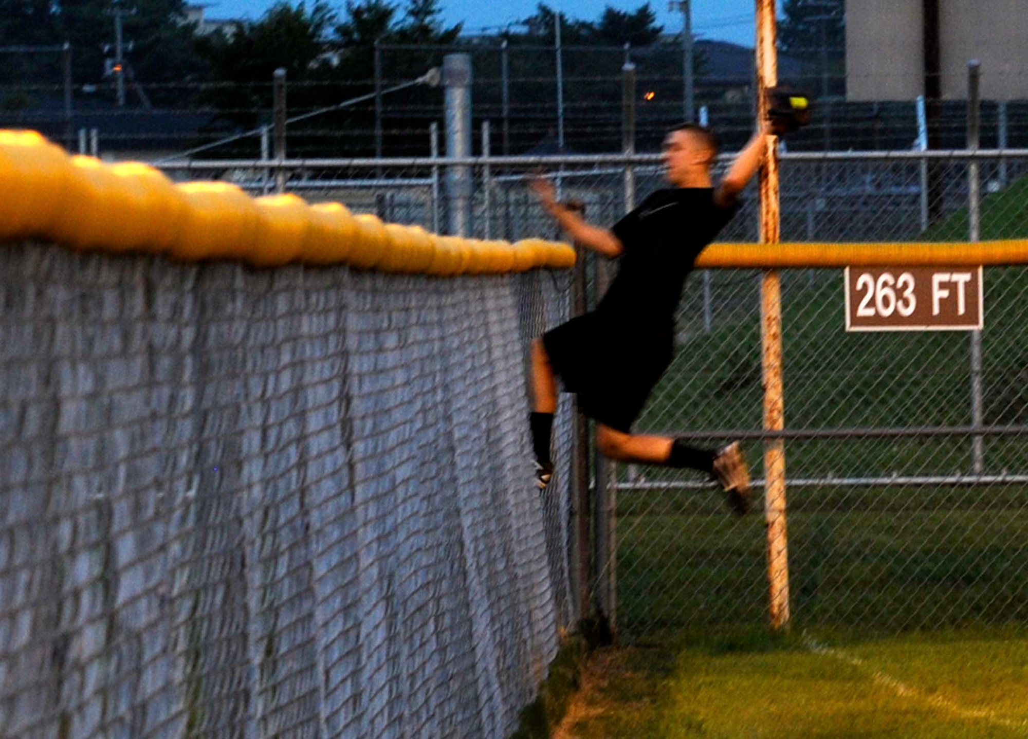 U.S. Navy Petty Officer 2nd Class Daniel D’Orsi, Commander Task Force 72 left fielder, makes a leaping catch off the fence in foul territory during the intramural softball championship game at Misawa Air Base, Japan, Aug. 1, 2012. The CTF-72 team was fourth place out of five top teams in the National League going into the playoffs before their championship run and victory. (U.S. Air Force photo by Airman 1st Class Zachary Kee/Released)