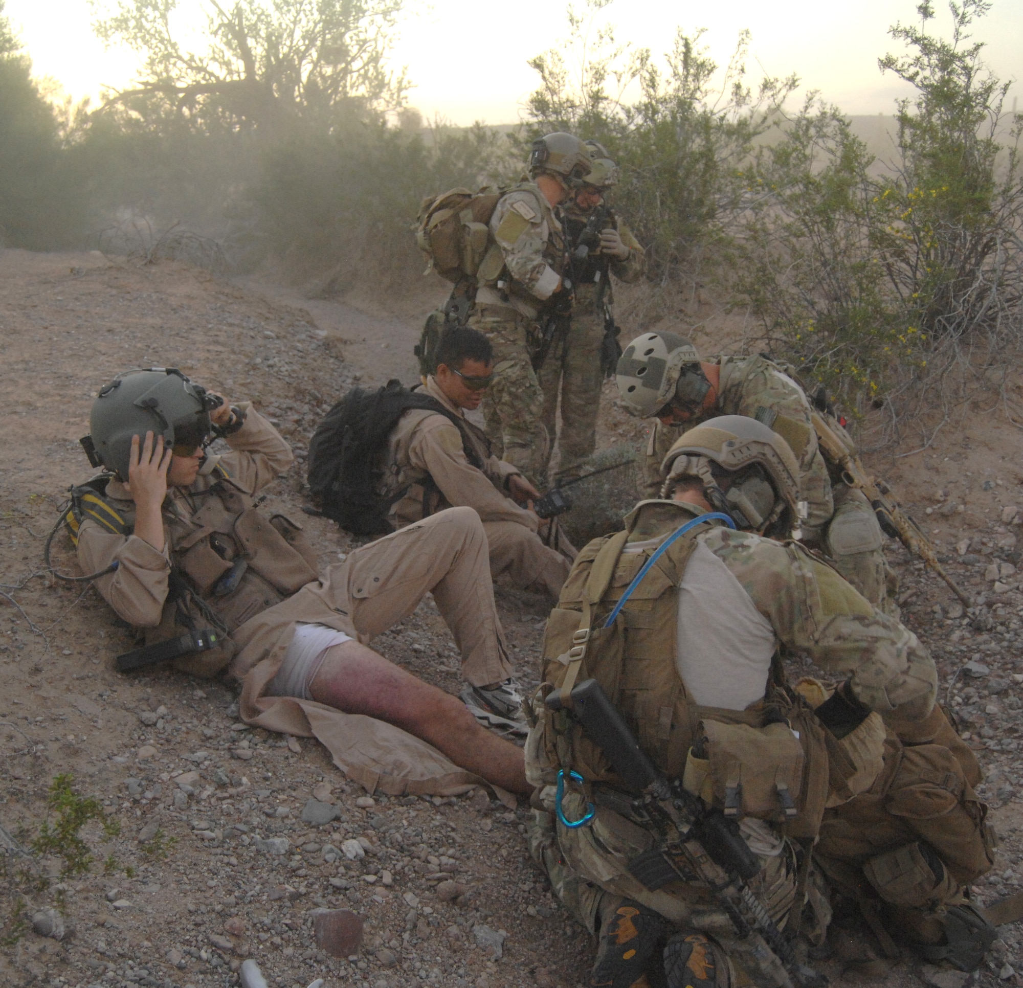 U.S. Air Force pararescuemen work diligently as they tend to the simulated injuries of the two survivors during a combat search and rescue training mission on July 25 at Gila Bend Air Force Auxiliary Field, Ariz. One survivor has an injured elbow, while the other has a broken ankle and femur. (U.S. Air Force photo by Airman 1st Class Michael Washburn/Released)