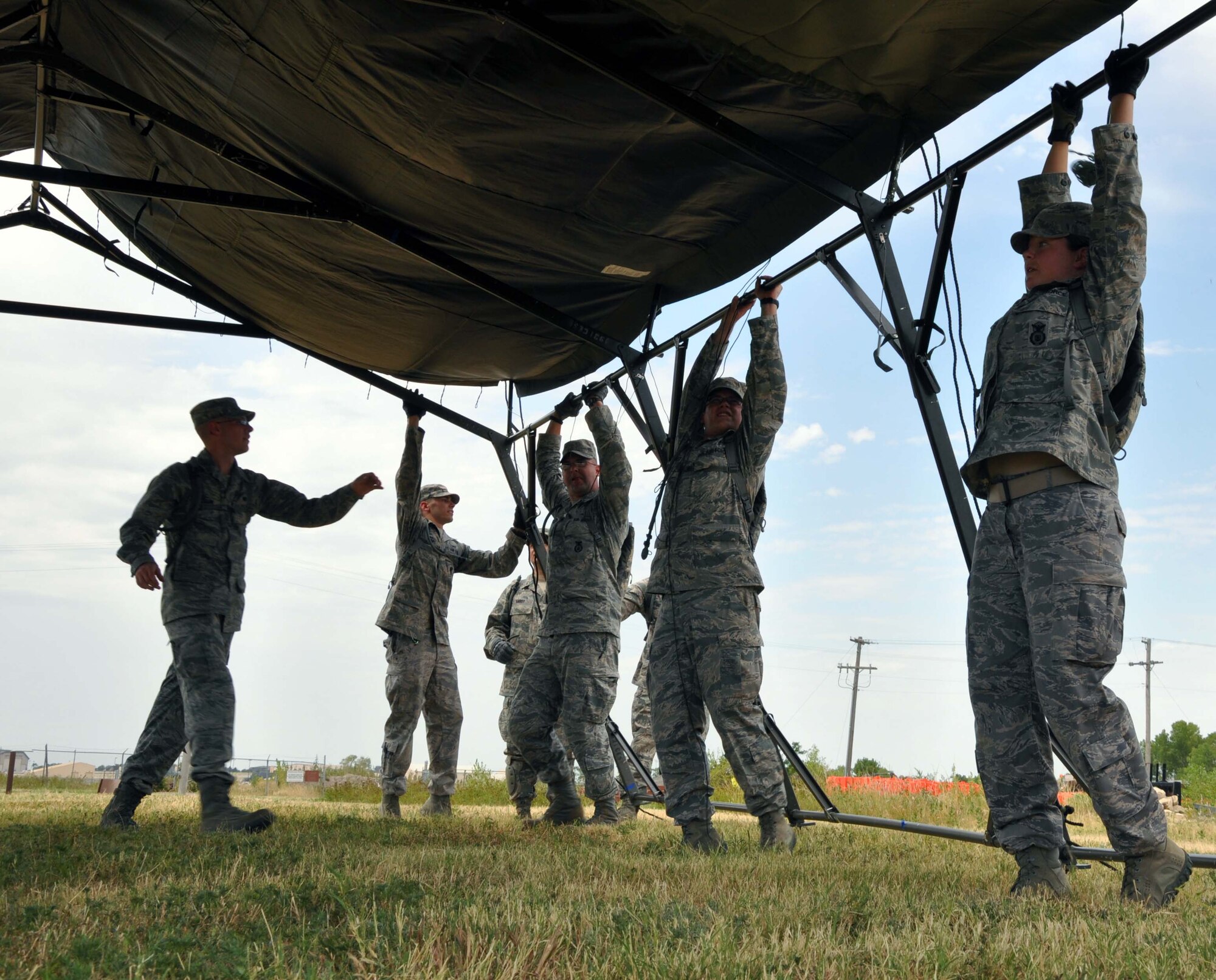 Members of the 931st Security Forces Squadron stretch to raise a portion of a Tent, Extendable, Modular, Personal (TEMPER) during a field training excercise conducted at McConnell Air Force Base, Kan., July 2, 2012.  The squadron is conducting a four-day field training excercise in order to prepare for future deployments.  Part of the training included instruction and application on how to assemble and break down the tent.  (U.S. Air Force photo by 1st Lt. Zach Anderson)