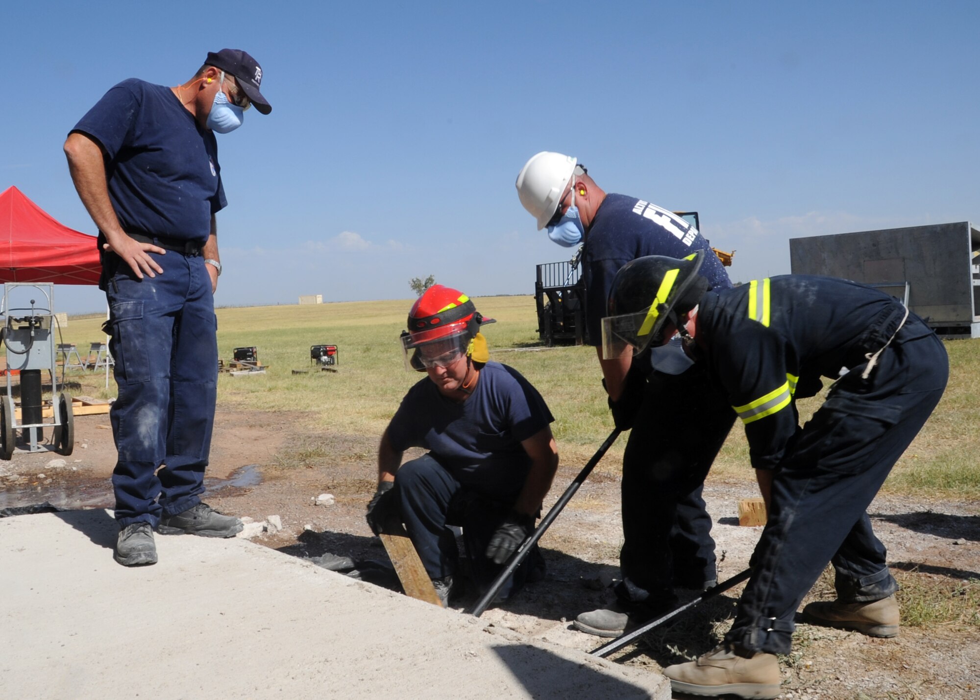 ALTUS AIR FORCE BASE, Okla. – Jim Carter, Tech-ResQ owner evaluates firefighters from the 97th Civil Engineer Squadron fire department as they pry up a concrete slab during a structural collapse exercise at the Altus AFB training pit, Aug. 3, 2012. Trainers from Tech-ResQ evaluated Members from the 97th CES fire department on an advanced structural collapse exercise, which helped the firefighters stay current on their training. The exercise simulated a collapsed building in which the firefighters had to cut holes in walls, floors and ceilings to access them. They also built shores to help support collapsing floors and ceilings. (U.S. Air Force photo by Airman 1st Class Franklin R. Ramos / 97th Air Mobility Wing / Released)