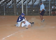 Navy Information Operations Command-Texas base runner Ross Beebe slides under the tag as 343rd Training Squadron catcher James Bice tries to take him out at home July 26 during the Joint Base San Antonio-Lackland intramural softball tournament championship game. Home plate umpire Jesse Jenkins called Beebe safe. NIOC-Texas, and the 343rd TRS will join the 802nd Force Support Squadron and the 624th Operations Center at the all-JBSA intramural softball tournament, which begins Monday at JBSA-Randolph. (U.S. Air Force photo/Alan Boedeker)
