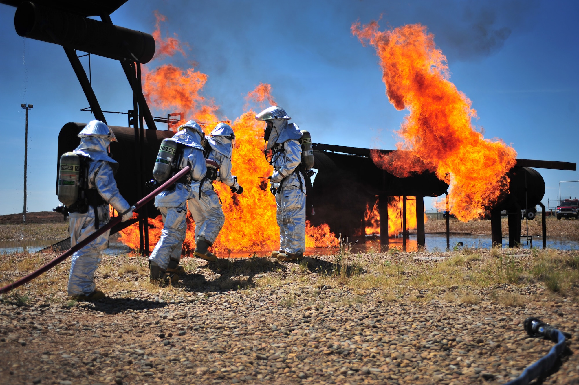 Firefighters with the 27th Special Operations Civil Engineer Squadron discuss strategies before entering the burn pit at Cannon Air Force Base, N.M., Aug. 2, 2012. The pit houses a replicated aircraft equipped with a propane tank and several igniters used to sustain training fires. (U.S. Air Force photo/Airman 1st Class Eboni Reece)
