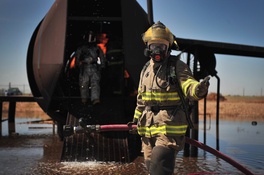 A member of the Clovis, N.M. Fire Department gestures for another member to follow her into the replicated aircraft in the burn pit at Cannon Air Force Base, N.M., Aug. 2, 2012. Clovis firefighters were able to utilize base training facilities to conduct required annual training to stay current on tactics and strategy. (U.S. Air Force photo/Airman 1st Class Eboni Reece)