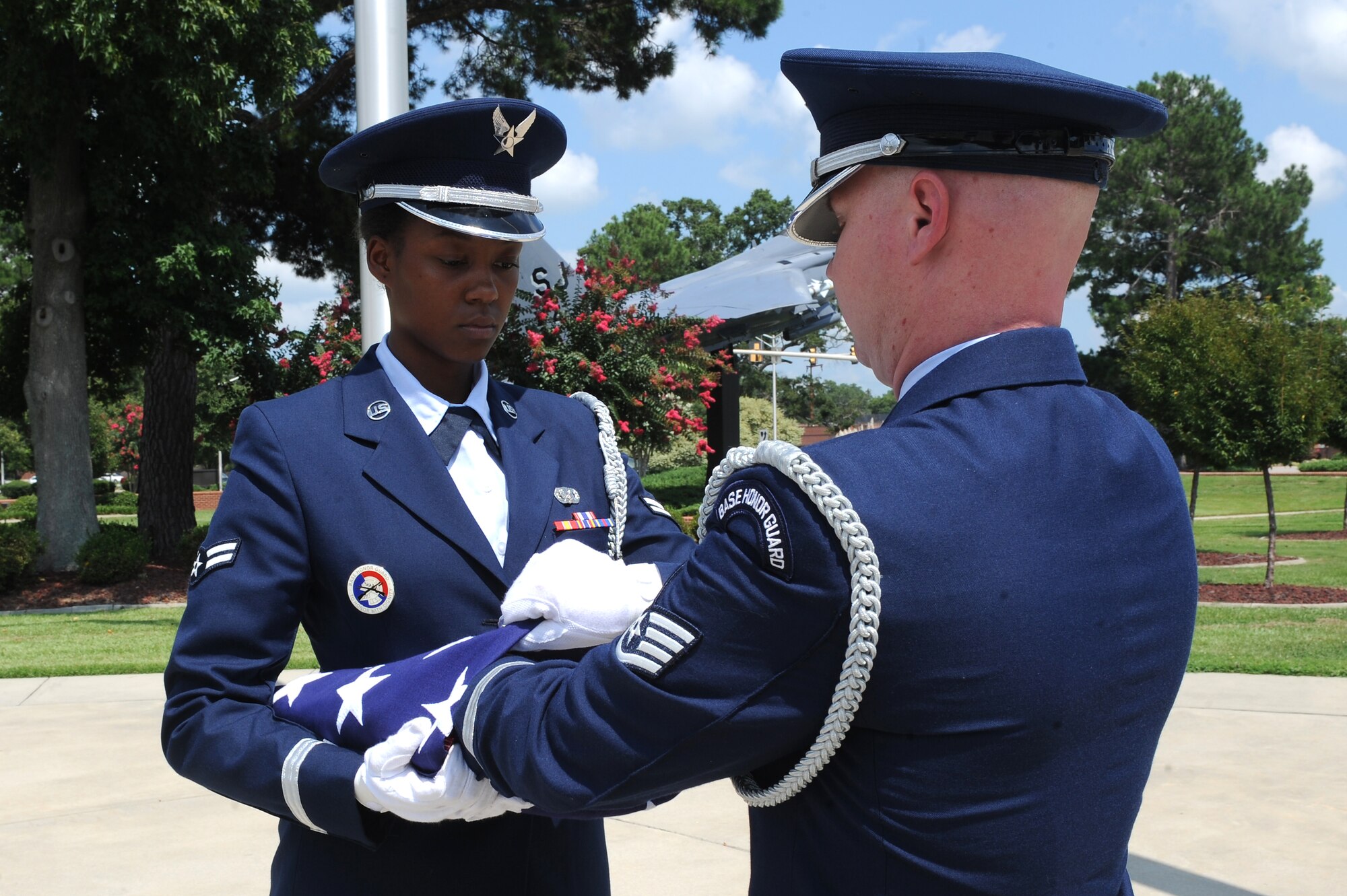 U.S. Air Force Airman 1st Class Stephanie Loftin, 4th Fighter Wing honor guardsman holds an American flag open as Staff Sgt. Frederick Burke, 4th FW honor guardsman, tucks in the final fold during a flag-folding ceremony on Seymour Johnson Air Force Base, N.C., July 31, 2012. The tradition of flag folding takes place at numerous events upon request such as retirements and funerals. (U.S. Air Force photo/Airman 1st Class John Nieves Camacho/Released)