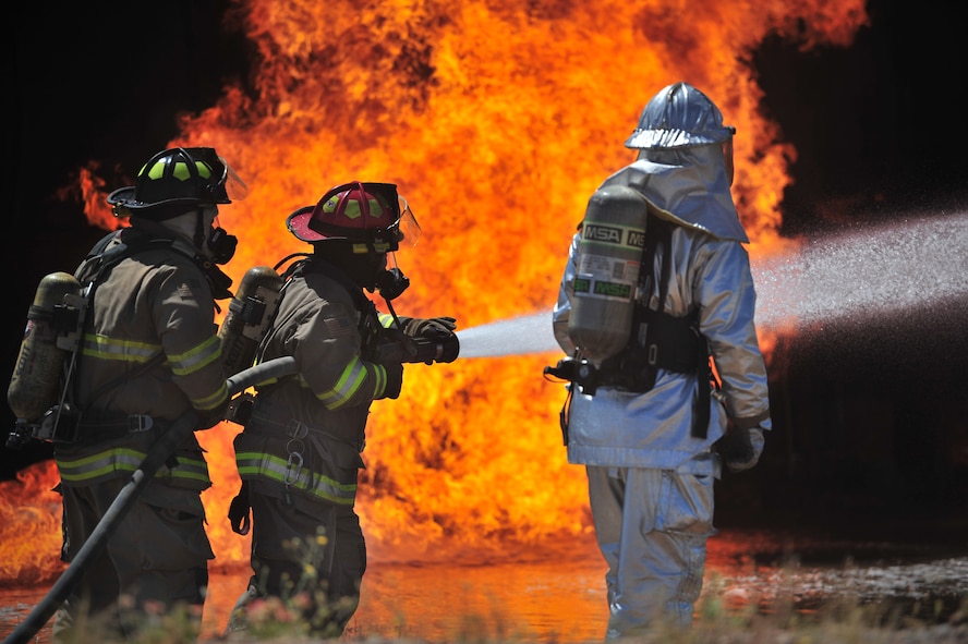 Firefighters with the Clovis, N.M. Fire Department and a firefighter with the 27th Special Operations Civil Engineer Squadron work to extinguish an engine fire in the burn pit at Cannon Air Force Base, N.M., Aug. 2, 2012. The pit houses a replicated aircraft equipped with a propane tank and several igniters used to sustain training fires. (U.S. Air Force photo/Airman 1st Class Alexxis Pons Abascal) 