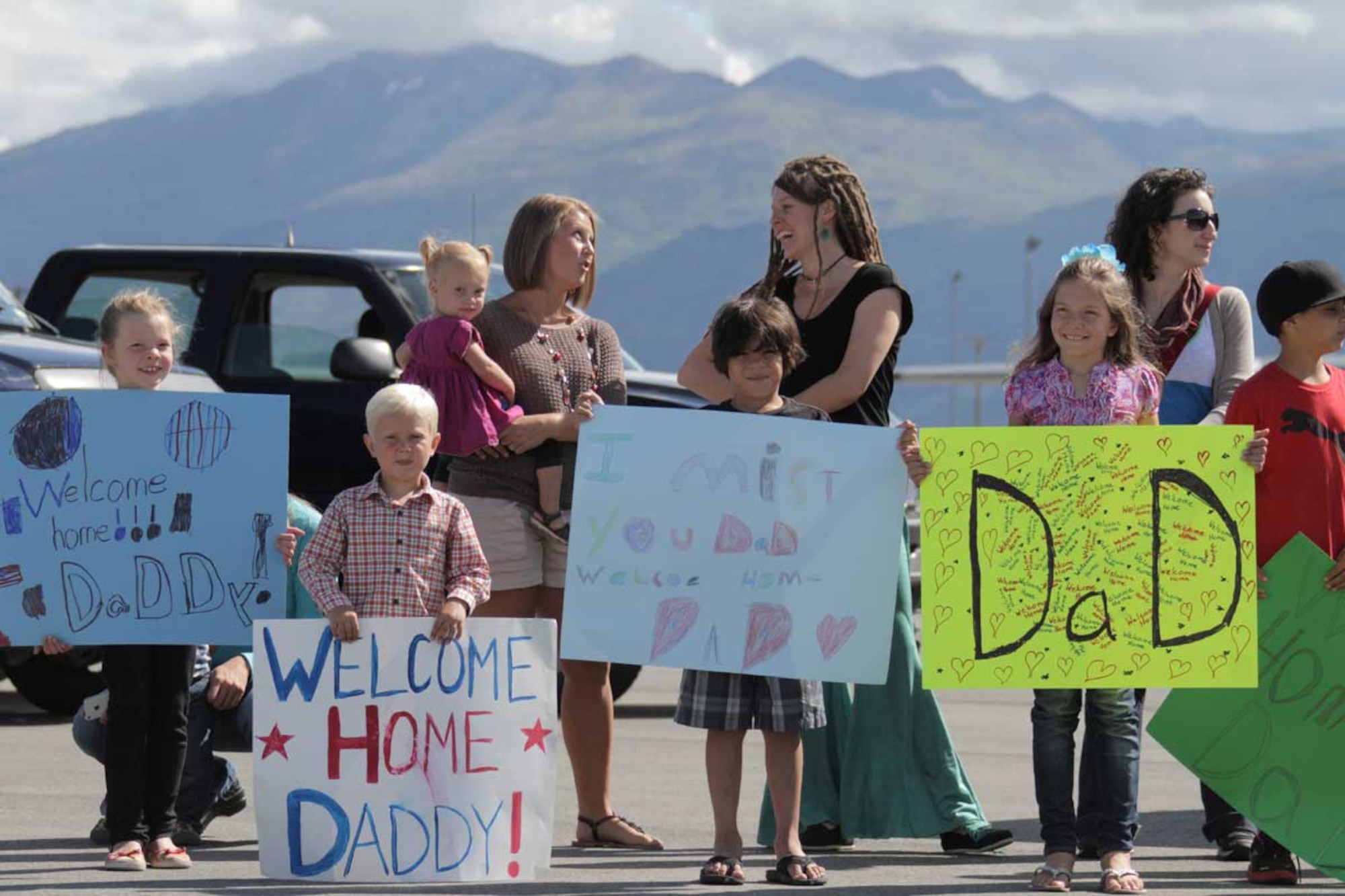 Family members hold welcome home signs while waiting for 212th RQS AIrmen to return home. (Alaska National Guard photo/Air Force Maj. Guy Hayes)