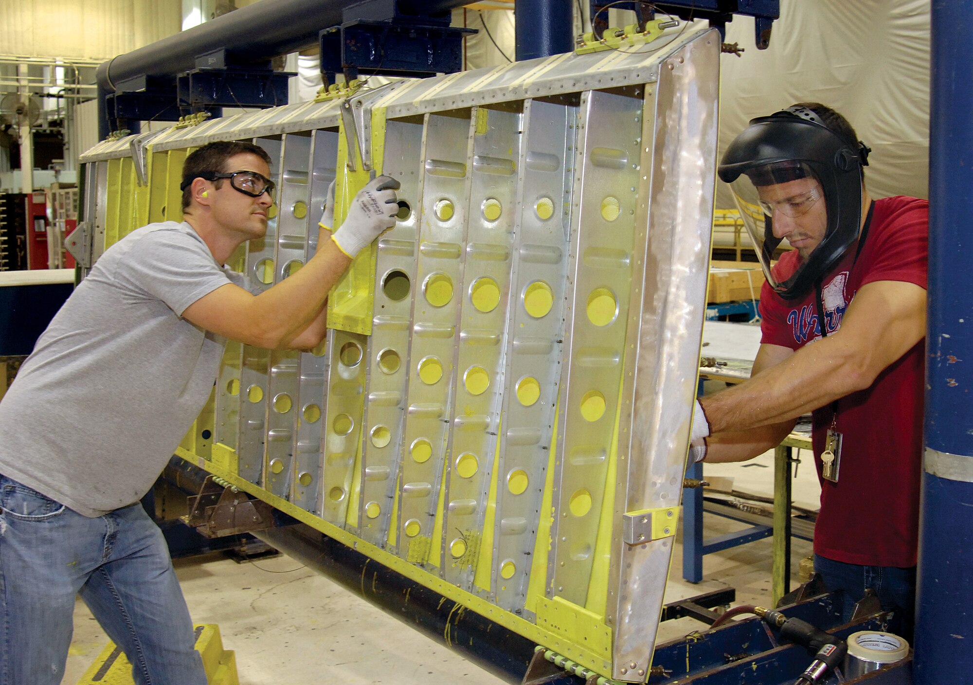 Sheet metal mechanics Randall McCoy, left, and Dustin Venegas reskin a KC-135 main landing gear door in the KC-135 Miscellaneous Shop of the 551st Commodities Maintenance Squadron, located in the sprawling Bldg. 9001 repair facility. (Air Force photos by Margo Wright)
