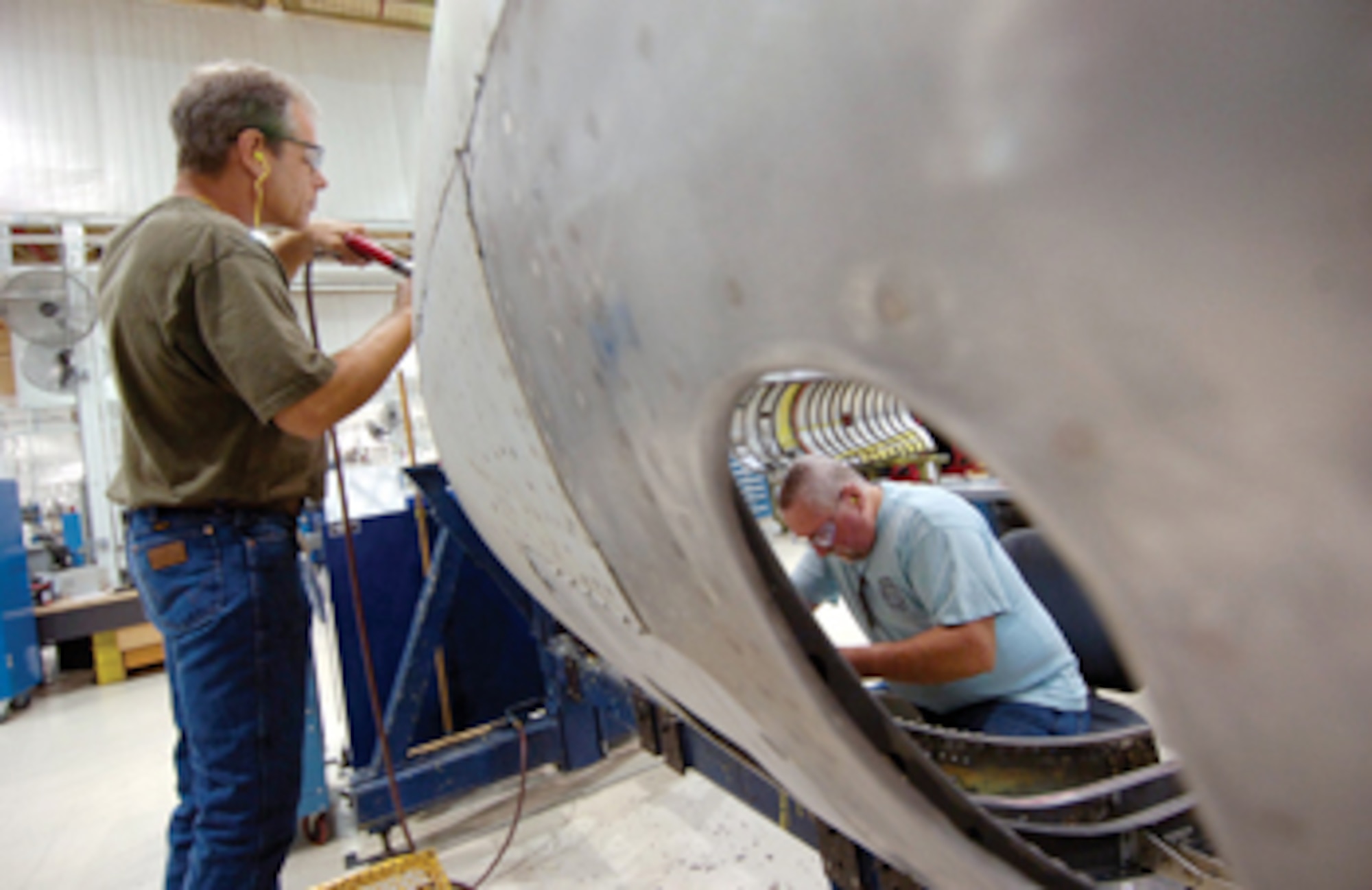 Tinker sheet metal mechanics Derek Kirkland, left, and Tom Hanselman tackle work on both sides of a B-52 side cowling, installing fittings and hinge pins that attach the cowling to the bomber. The men are with the 551st Commodities Maintenance Squadron’s B-52 and E-3 Side Cowling Shop located in Bldg. 9001. (Air Force photos by Margo Wright)