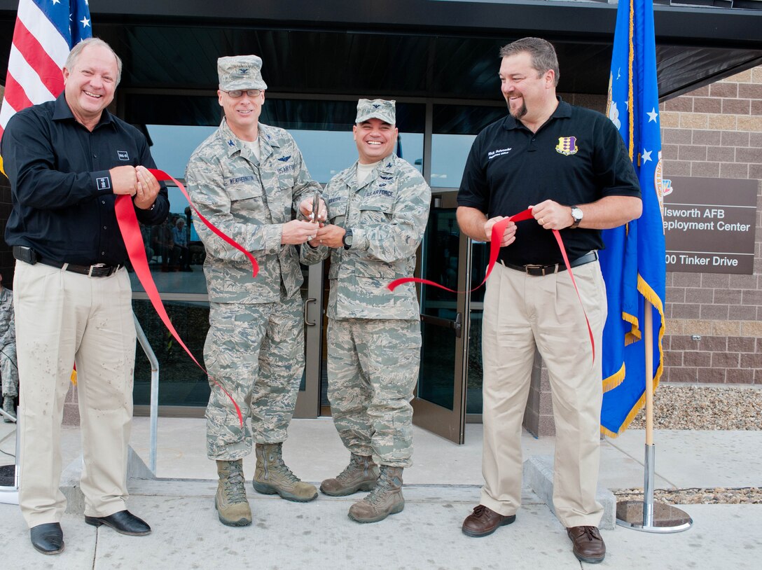 Dale Satterthwaite, Big D Construction vice president, Col. Mark Weatherington, 28th Bomb Wing commander, Col. Thomas Goulter, 28th Mission Support Group commander, and Rick Schroeder, 28th Logistics Readiness Squadron installation deployment officer, cut a ribbon to commemorate the official opening of the new deployment center at Ellsworth Air Force Base, S.D., Aug. 2, 2012. The $16.9 million facility optimizes the deployment processes of the base by housing all aspects of passenger and cargo processing under one roof. (U.S. Air Force photo by Airman 1st Class Zachary Hada/Released)