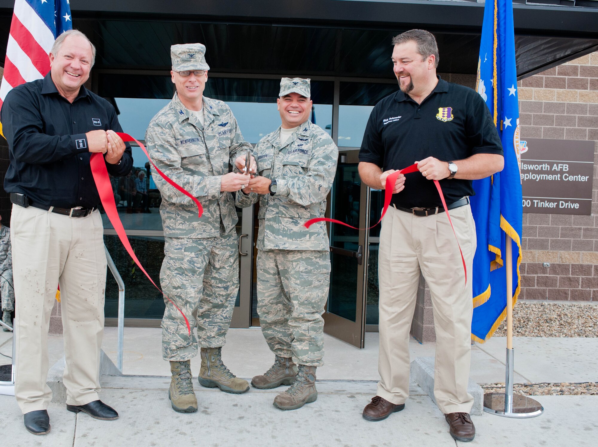 Dale Satterthwaite, Big D Construction vice president, Col. Mark Weatherington, 28th Bomb Wing commander, Col. Thomas Goulter, 28th Mission Support Group commander, and Rick Schroeder, 28th Logistics Readiness Squadron installation deployment officer, cut a ribbon to commemorate the official opening of the new deployment center at Ellsworth Air Force Base, S.D., Aug. 2, 2012. The $16.9 million facility optimizes the deployment processes of the base by housing all aspects of passenger and cargo processing under one roof. (U.S. Air Force photo by Airman 1st Class Zachary Hada/Released)