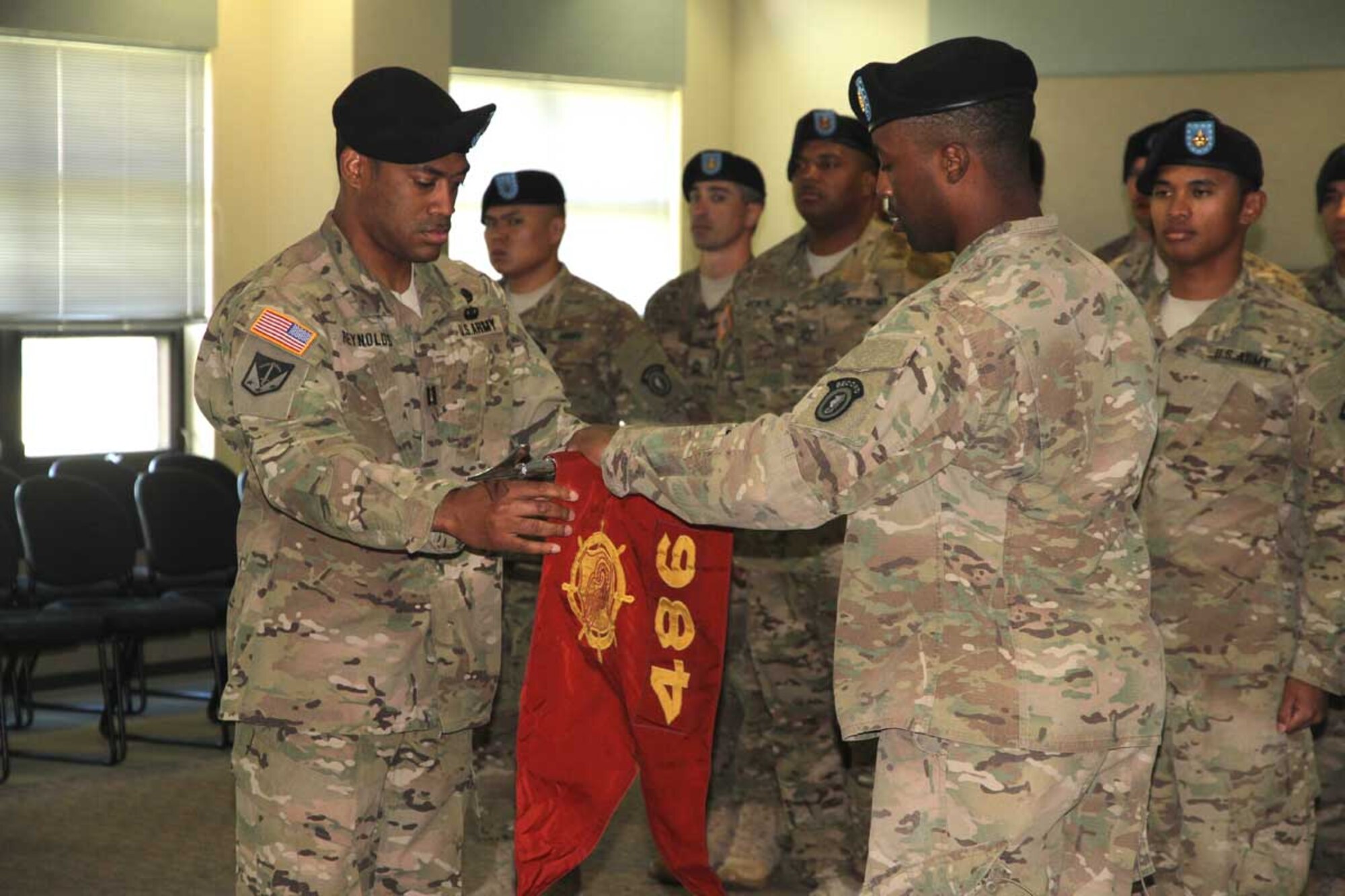 Army Capt.  Antonio Reynolds, 486th MCT company commander, and Sgt. 1st Class Tarik Smith, 486th MCT first sergeant, uncase the unit’s guidon during the MCT’s redeployment ceremony Tuesday at the Richardson Education Center.Soldiers of the MCT redeployed from a yearlong mission throughout Kuwait and Afghanistan. The uncasing of the guidon signified the unit’s successful completion of a combat deployment and subsequent reintegration into U.S. Army Alaska.  (U.S. Army photo/Sgt. Tamika Dillard)
