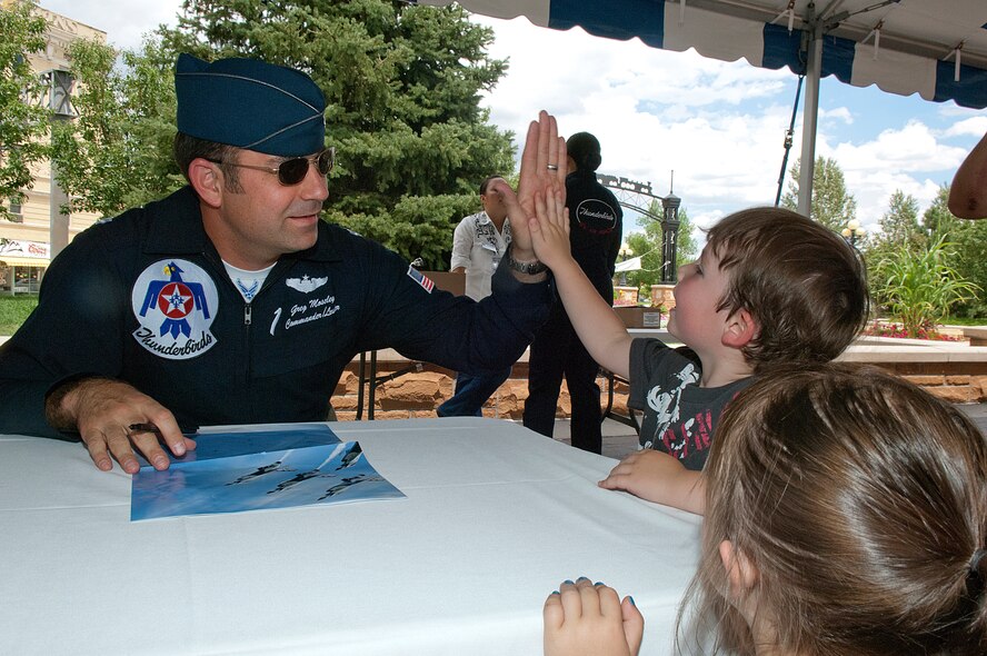 Lt. Col. Greg Moseley, U.S. Air Force Thunderbirds commander, high-fives Brady Benne, 4, as his sister, Madison Benne, 2, looks on. The Thunderbirds held an autograph session July 24 in Cheyenne, Wyo., the day before their airshow. (U.S. Air Force photo by R.J. Oriez)