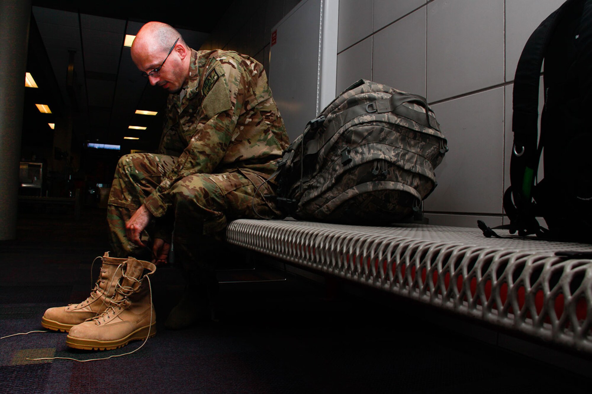 Staff Sgt. Brian Barnes, 911th Airlift Wing cyber operations specialist, laces up his boot after going through a security checkpoint at the Pittsburgh International Airport, August 2, 2012. Barnes is deploying to an undisclosed location in southwest Asia in support of Operation Enduring Freedom. (U.S. Air Force photo by Senior Airman Justyne Obeldobel/Released)
