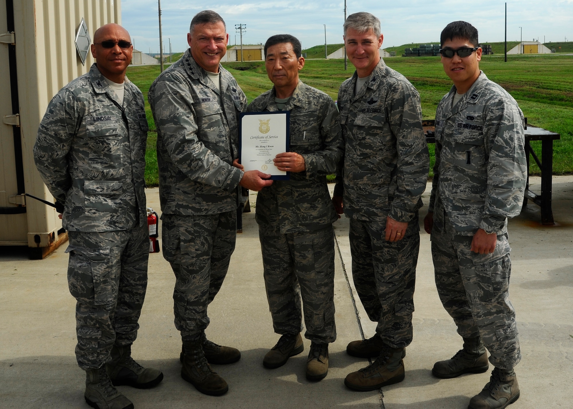 Gen. Gary North, Pacific Air Forces commander, awards Hong Kwon, 8th Maintenance Squadron explosive operator, with a certificate of service for his 30 years of service at Kunsan Air Base, Republic of Korea, July 18, 2012. The general was joined by Col. Ray Lindsay, 8th Maintenance Group commander, left, Col. John Pearse, 8th Fighter Wing commander, and Capt. Hoyoon Chung, 8th Maintenance Squadron mission flight commander. Hong inspects and maintains a wide range of explosive ordnance and munitions for the base. Hong was one of five civilians awarded for his 30 years of service to Kunsan. (U.S. Air Force photo/Senior Airman Marcus Morris)
