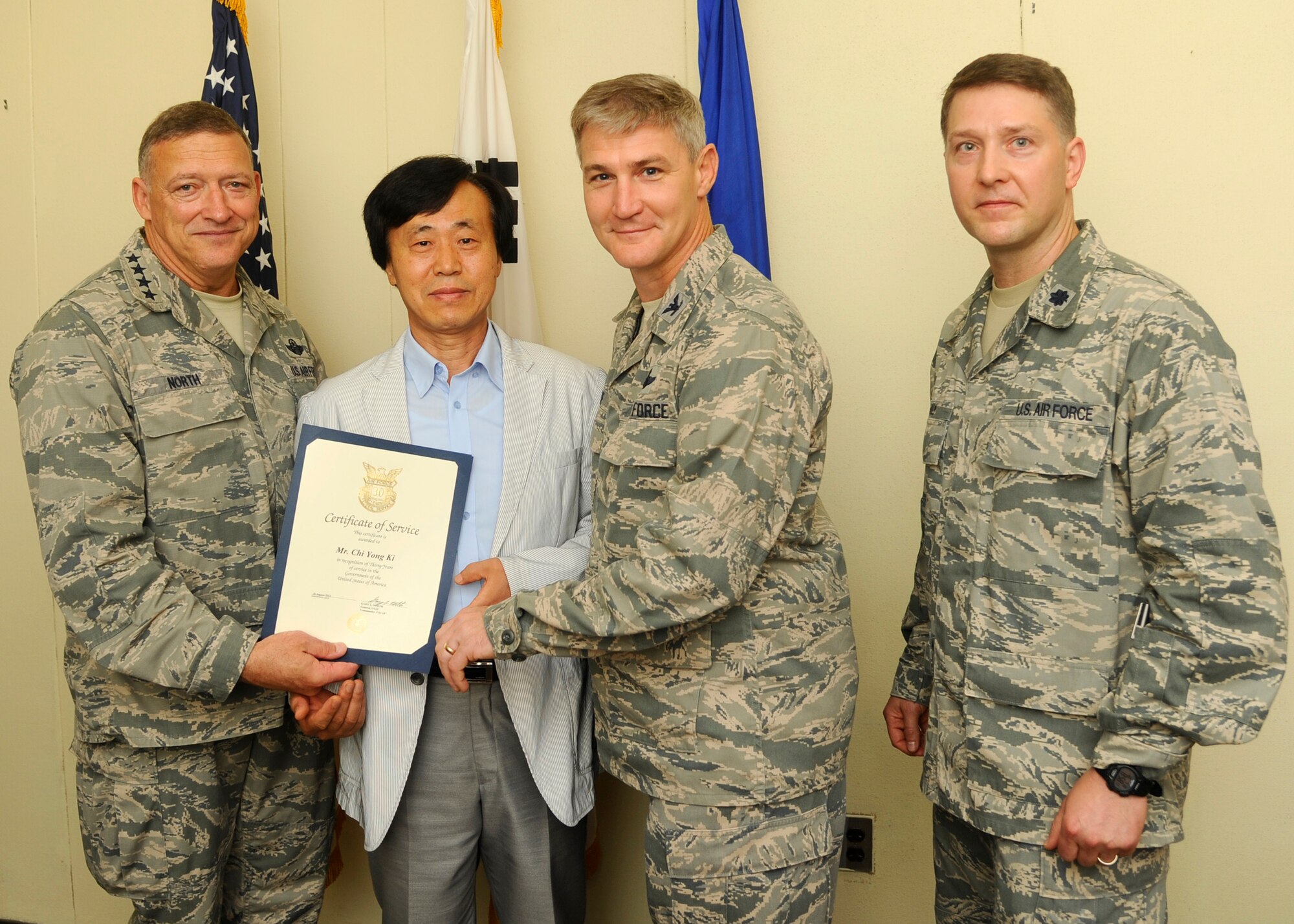 Gen. Gary North, Pacific Air Forces commander, along with Col. John Pearse, 8th Fighter Wing commander, and Lt Col. Trenton Maly, 8th Force Support Squadron commander, awards Chi Yong Ki, 8th Force Support Squadron resource manager, with a certificate of service for his 30 years of service at Kunsan Air Base, Republic of Korea, July 18, 2012. Chi serves as the chief of the funds control section for the non-appropriated funds accounting office and supervises, manages and directs the section to ensure cash controls are effective, financial data is accurate and payments are timely.  (U.S. Air Force photo/Senior Airman Marcus Morris)