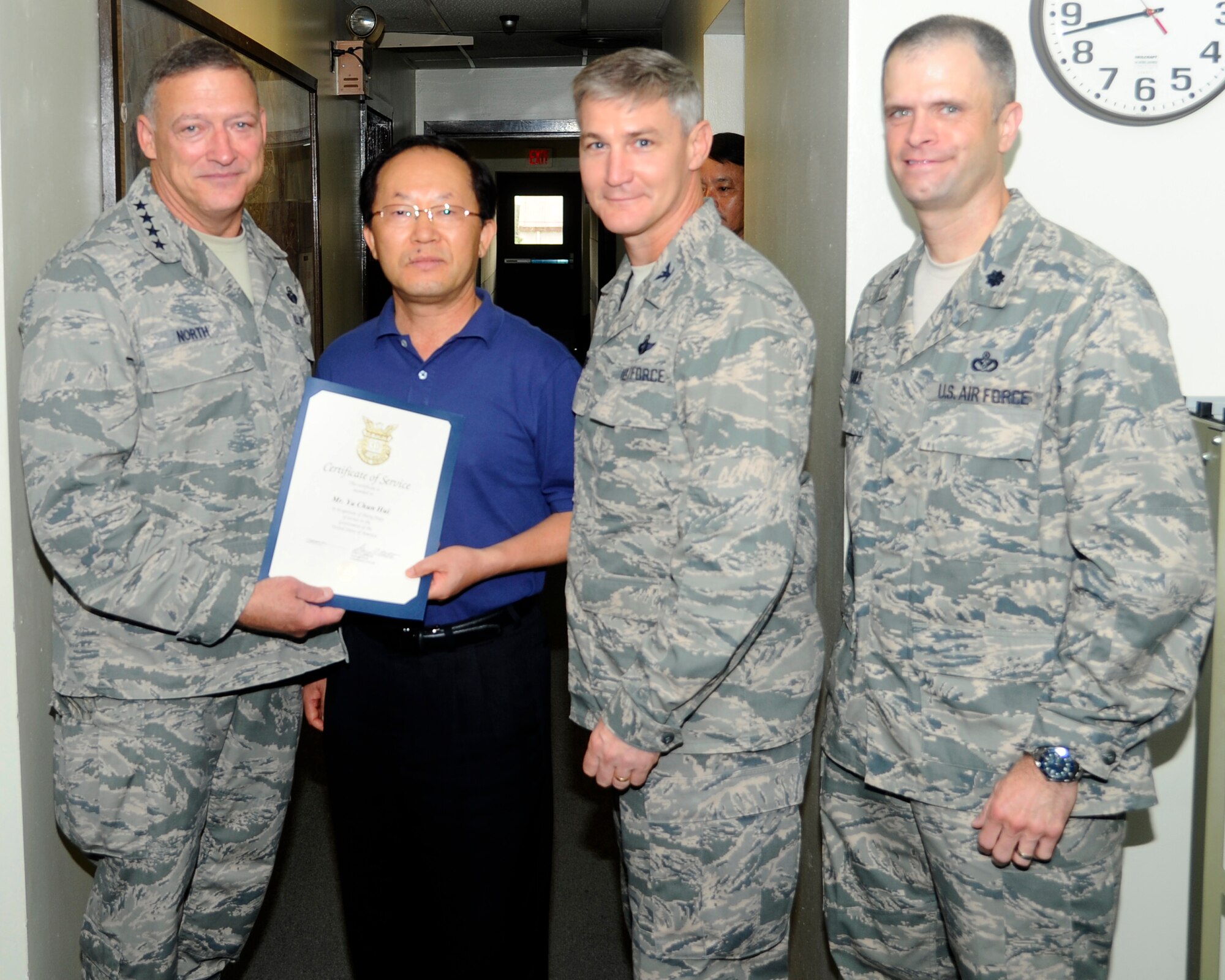 Gen. Gary North, Pacific Air Forces commander, along with Col. John Pearse, 8th Fighter Wing commander, and Lt Col. Deron Frailie, 8th Civil Engineer Squadron commander, awards Yu Chun Hui, 8th Civil Engineer Squadron environmental engineer section chief, with a certificate of service for his 30 years of service at Kunsan Air Base, Republic of Korea, July 18, 2012. As the senior environmental engineer for Kunsan, Yu provides oversight on all environmental programs and ensures compliance with environmental initiatives for the 8th Fighter Wing. Yu is one of five civilians honored for their 30 years of service to Pacific Air Forces. (U.S. Air Force photo/Senior Airman Marcus Morris)