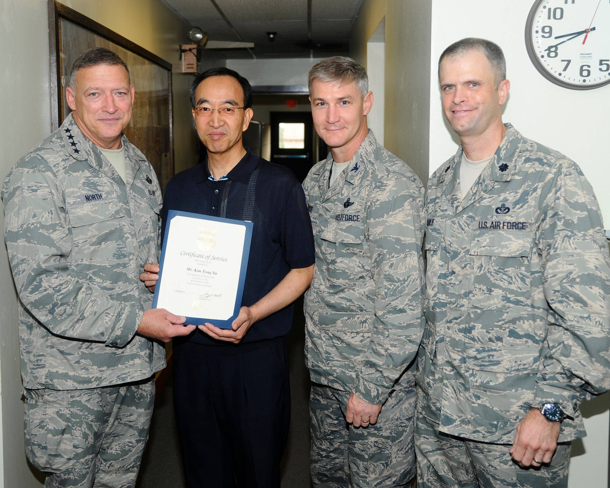 Gen. Gary North, Pacific Air Forces commander, along with Col. John Pearse, 8th Fighter Wing commander, and Lt Col. Deron Frailie, 8th Civil Engineer Squadron commander, awards Kim Tong Su, 8th Civil Engineer Squadron project programmer, with a certificate of service for his 30 years of service at Kunsan Air Base, Republic of Korea, July 18, 2012. Kim manages all new construction, facility maintenance and repair requirements for Kunsan and is one of five civilians who were awarded this honor by North.  (U.S. Air Force photo/Senior Airman Marcus Morris)