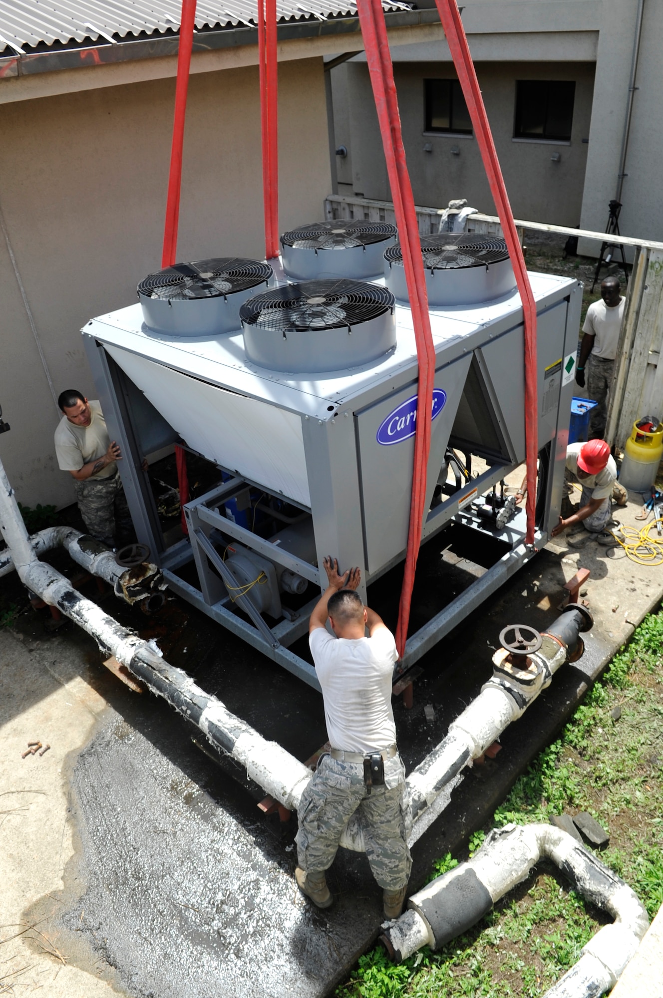 Members from the 8th Civil Engineer Squadron heating, ventilation and air conditioning shop position a new AC July 30, 2012, at Kunsan Air Base, Republic of Korea. The HVAC shop is responsible for maintaining cooling and heating units at nearly 300 Kunsan facilities. (U.S. Air Force photo/Senior Airman Brigitte N. Brantley)