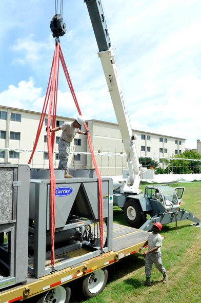 Members from the 8th Civil Engineer Squadron pavements and equipment shop prepare to move a new air conditioner into place near a dormitory at Kunsan Air Base, Republic of Korea, July 30, 2012. The daylong project required coordination from three shops in the squadron to provide air conditioning for 100 Airmen. (U.S. Air Force photo/Senior Airman Brigitte N. Brantley)