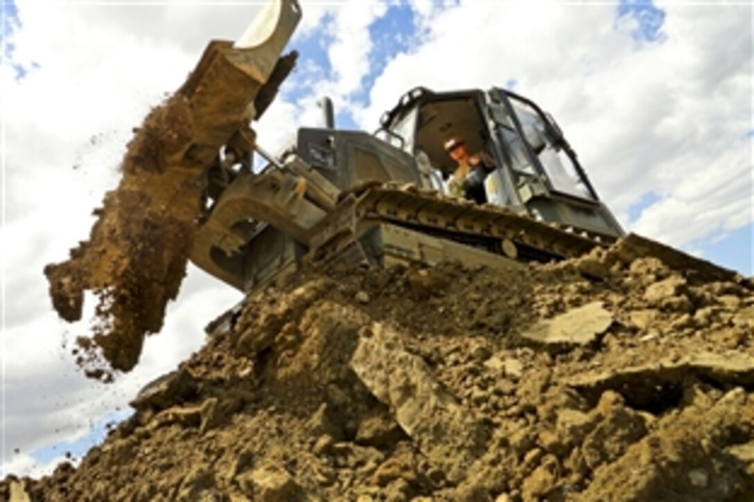 U.S. Navy Petty Officer 3rd Class Kenneth Menzies creates a stockpile of dirt that will be used to fill low spots in a demolition project at Naval Air Station Sigonella, Italy, July 25, 2012. The battalion is an expeditionary naval construction element assigned to U.S. 6th Fleet's Commander, to provide construction, engineering and security services for humanitarian assistance and contingency operations. Menzies is assigned to Naval Mobile Construction Battalion 3.