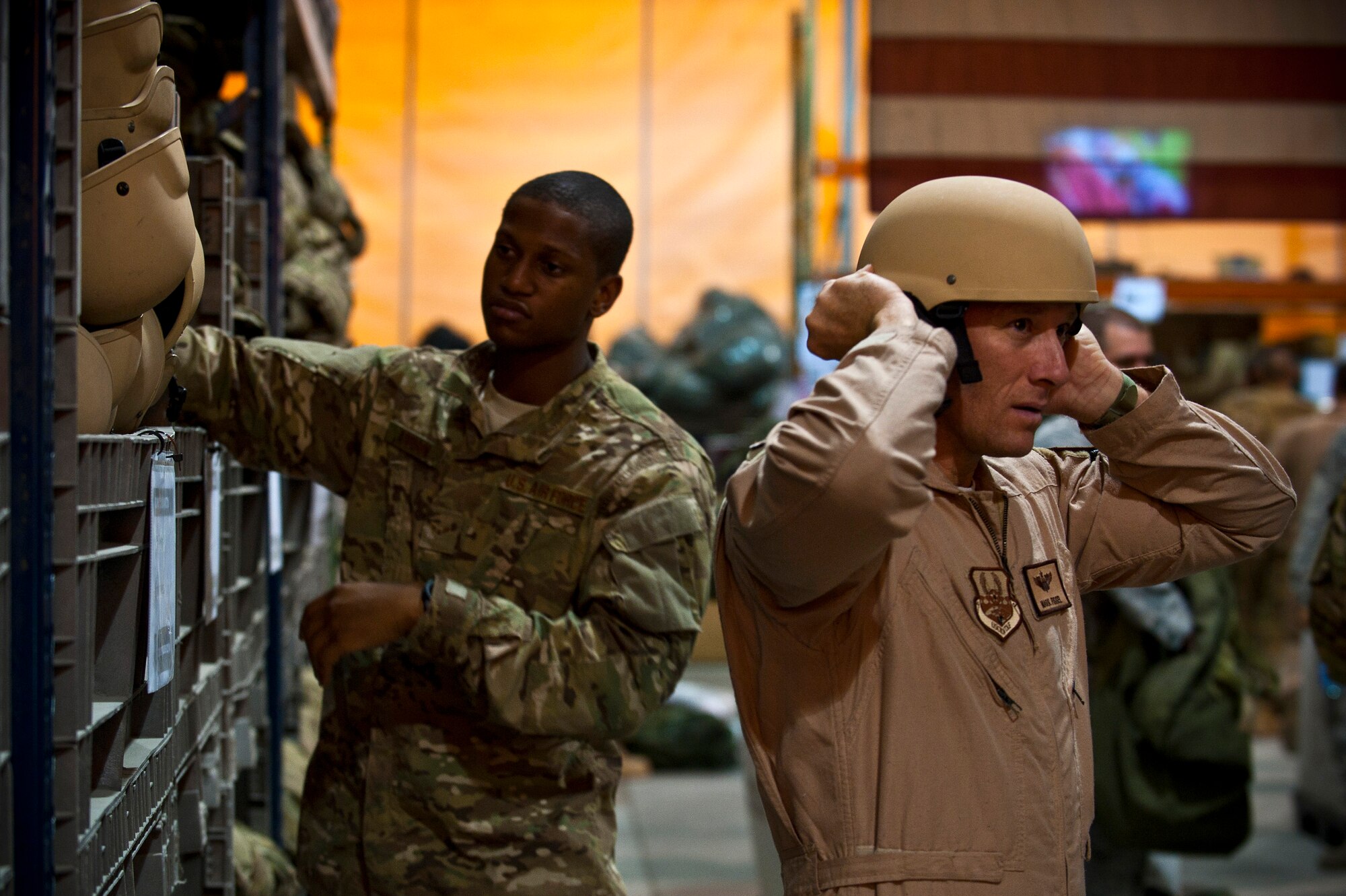 Airman 1st Class Brian Addison (left) and Maj. Mark Fissel try different kevlar helmet sizes at the Transit Center at Manas, Kyrgyzstan, August 4, 2012. The Transit Center's Expeditionary Theater Distribution Center is where Airmen and Air Force civilians deploying to Afghanistan receive protective gear. Addison is a air transportation journeyman deployed out of Yokota Air Base, Japan and is a native of Cleveland, Ohio. Fissel is a T-1 pilot instructor deployed out of Randolph Air Force Base, Texas. He is a native of San Marcus, Texas. (U.S. Air Force photo/Senior Airman Brett Clashman)
