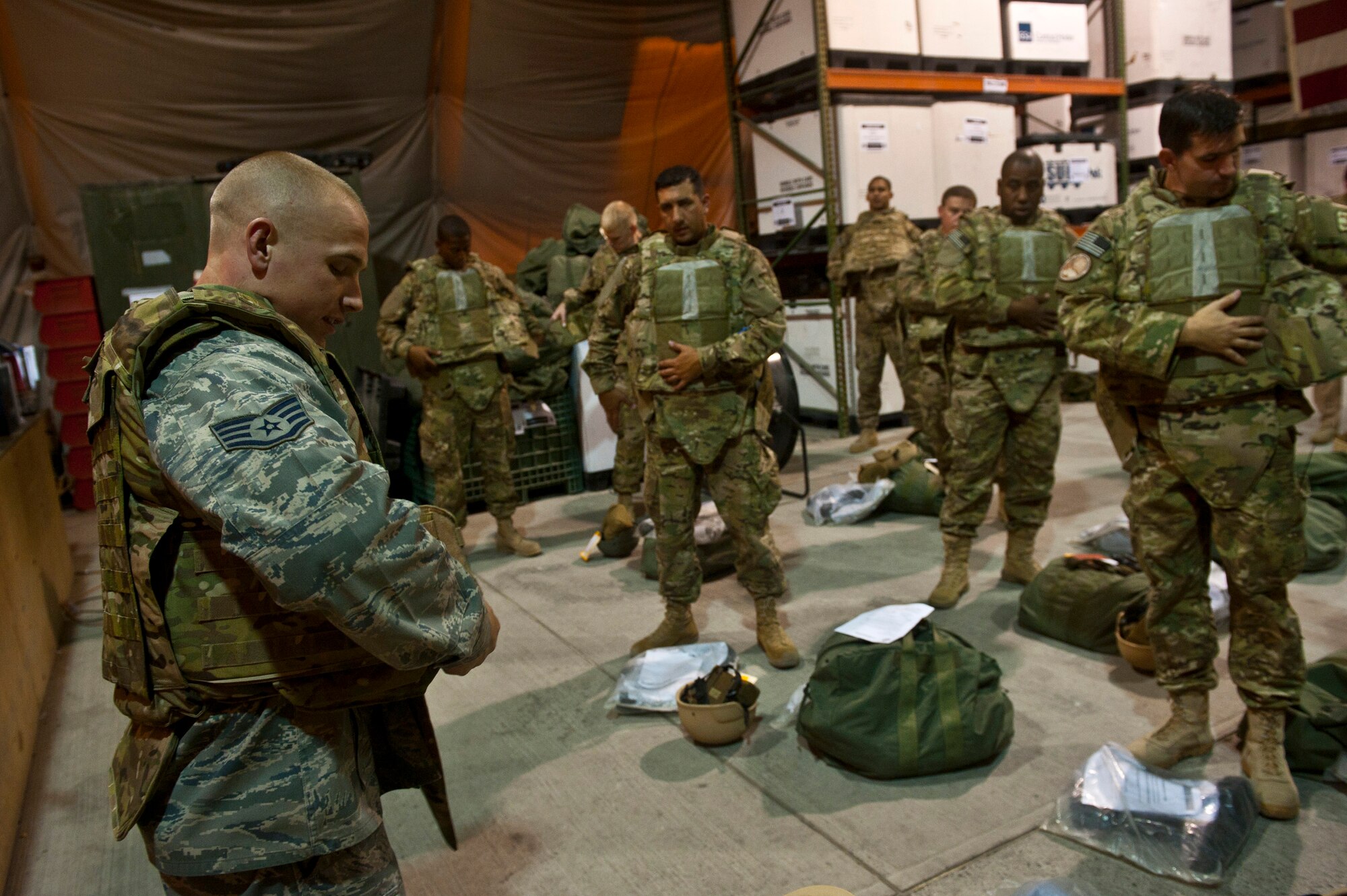 Staff Sgt. Seth Tuggle demonstrates how to properly wear a tactical vest to transient Airmen during equipment distribution at the Transit Center at Manas, Kyrgyzstan, Aug. 4, 2012. The Transit Center's Expeditionary Theater Distribution Center equipment technicians assist transiting personnel daily on how to properly wear individual protective gear. Tuggle is a Transit Center ETDC equipment technician deployed out of Little Rock Air Force Base, Ark. and is a native of Morton, Ill. (U.S. Air Force photo/Senior Airman Brett Clashman)