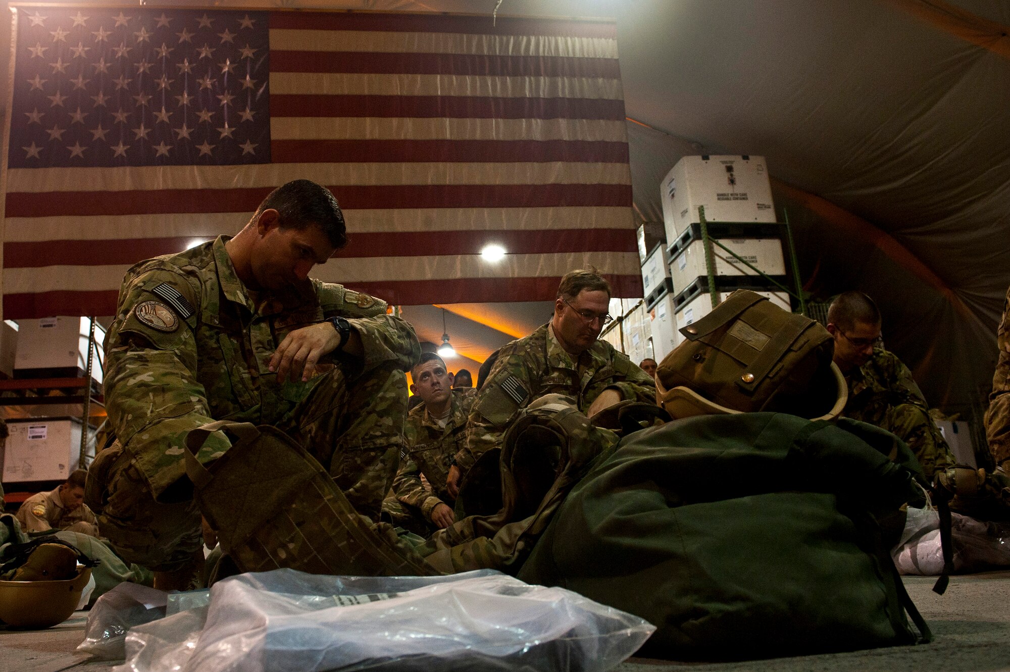 Transient Airmen wait for instructions on assembling individual protective equipment during equipment distribution at the Transit Center at Manas, Kyrgyzstan, Aug. 4, 2012. The Transit Center's Expeditionary Theater Distribution Center equipment technicians assist deployers and redeployers 24 hours a day, 365 days a year. (U.S. Air Force photo/Senior Airman Brett Clashman)