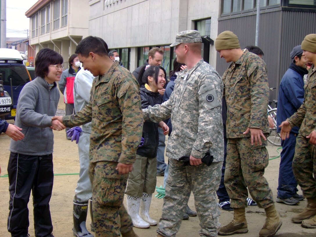 Local citizens of Ishinomaki City show their appreciation of Operation Tomodachi U.S. military members as they shake hands in mid March.  (Photo by Capt. Alex Glade)
