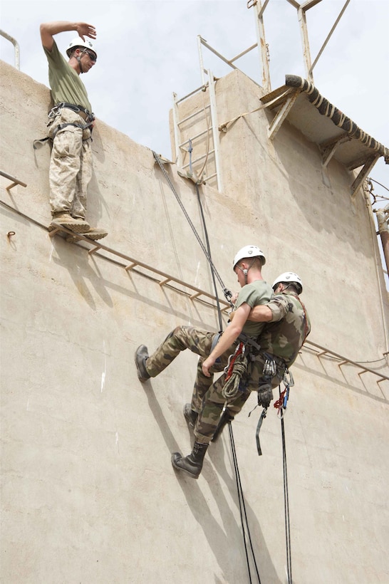 French forces Sgt. Jerome Dousse, 5th 
Marine Regiment, carries Sgt. Steven Rey down a training wall while U.S. Marine Master Sgt. Chris Brueggeman, 24th Marine Expeditionary Unit assault climbing instructor, supervises July 22. The French and U.S. Marines participated in an assault climbing course in the rugged terrain of the Arta Range July 19 - 30.