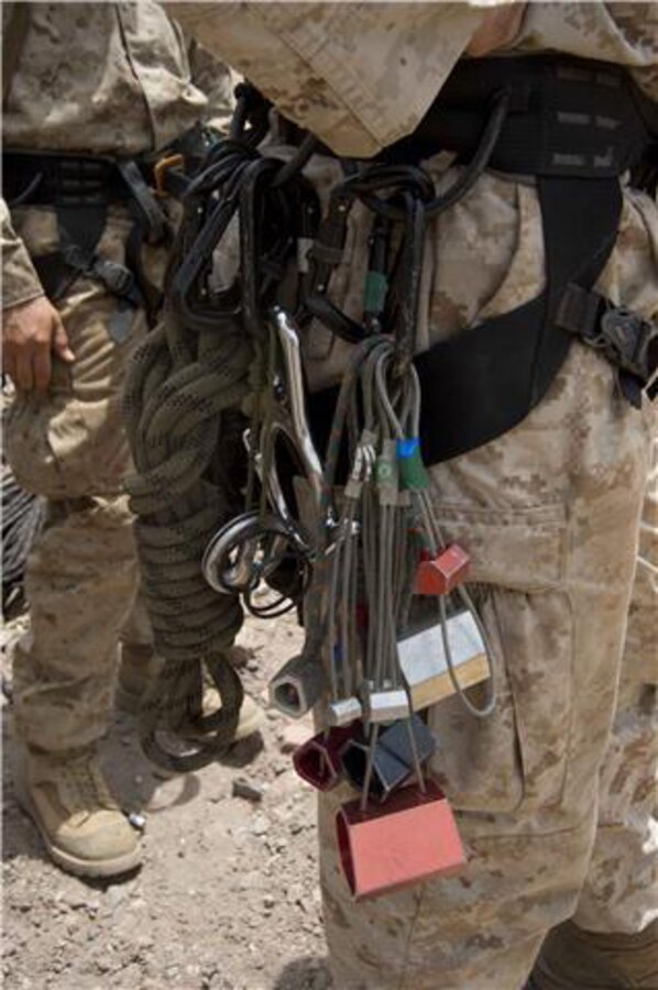 Rock climbing gear hangs from a U.S. Marine's harness July 22. French and U.S. Marines participated in an assault climbing course in the rugged terrain of the Arta Range July 19 - 30. The gear used by the Marines for rock climbing can include safety helmets, ropes, belay devices, carabiners, climbing harnesses, climbing shoes, quickdraws, crampons, and ice axes.