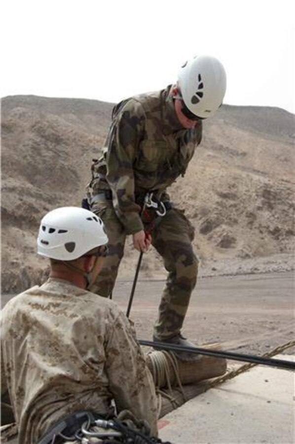French marine Sgt. Steven Rey, 5th Marine Regiment, prepares to jump off and repel down a cliff July 22 under the supervision of U.S. Marine Master Sgt. Chris Brueggeman, 24th Marine Expeditionary Unit assault climbers instructor. French and U.S. Marines participated in an assault climbing course in the rugged terrain of the Arta Range July 19 - 30. 