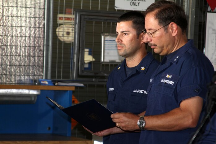 Rear Adm. Joseph 'Pepe' Castillo, Commander 11th Coast Guard District, holds the award citation of Petty Officer 2nd Class Matthew Garrison, Maritime Enforcement Specialist, Maritime Safety and Security Team San Diego aboard Marine Corps Recruit Depot San Diego Aug. 6. Garrsion was awarded the Coast Guard Achievment Medal for using cardiopulmonary resuscitaion to save a childs life. Approximately 30 fellow servicemembers attented the ceremony as well as local media. 