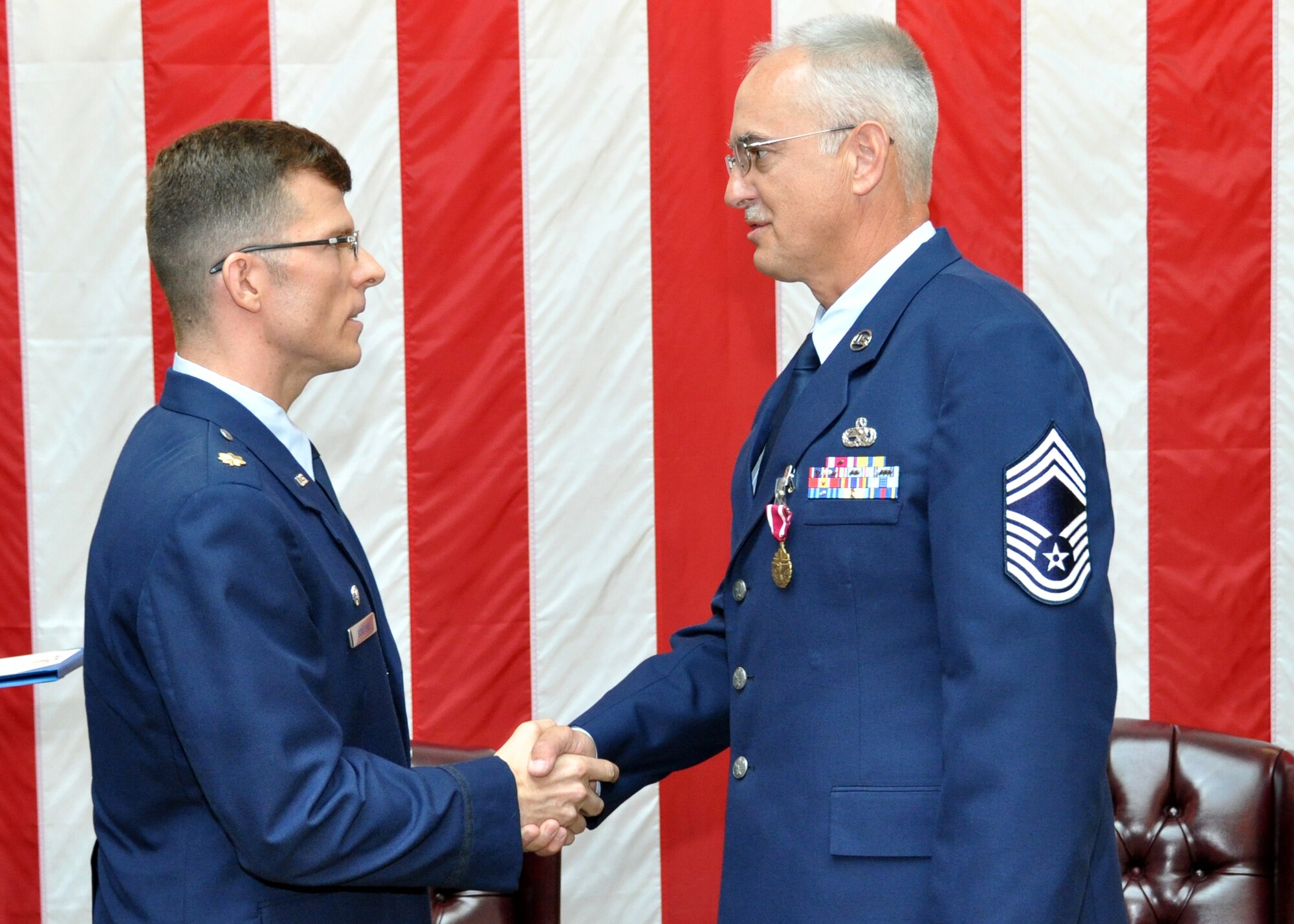 TRAVIS AIR FORCE BASE, Calif. -- Maj. Michael Savitsky, 349th AMXS commander, congratulates Chief Master Sgt. Mike Protsman, 349th AMXS superintendent, after presenting him the Meritorious Service Medal at his retirement ceremony, here B-Flight July. (U.S. Air Force photo/Master Sgt. Robert Wade)