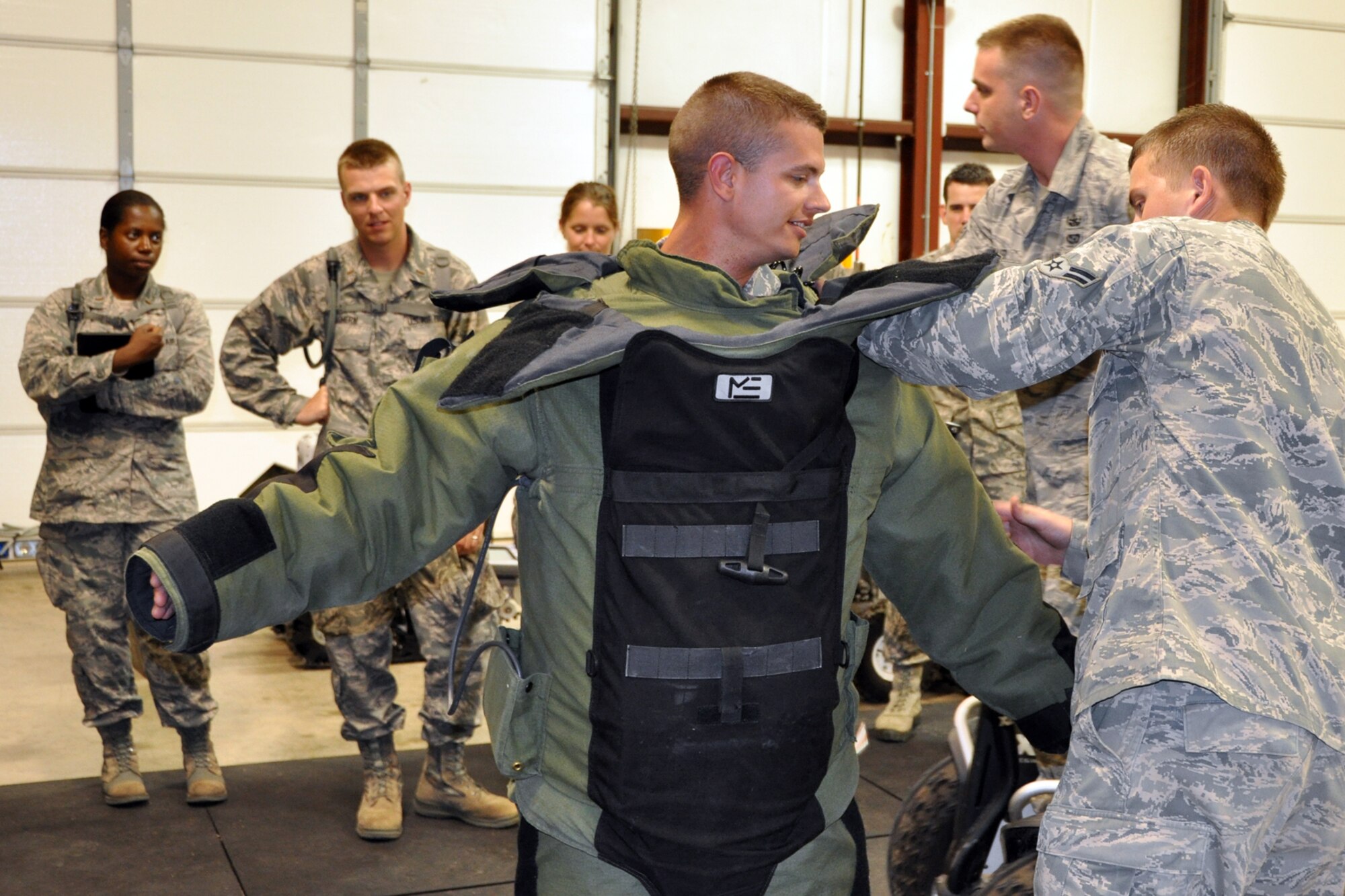 Airman 1st Class T.J. Brantley, an explosive ordinance disposal technician, assists Chaplain Candidate 2nd Lt. Sean Kilgo with the EOD -9 Bomb suit in the EOD complex at Barksdale Air Force Base, La., July 31, 2012. The suit weighs approximately 70 pounds. Brantley is assigned to the 2nd Civil Engineer Squadron, Explosive Ordinance Disposal Flight at Barksdale. (U.S. Air Force photo by Master Sgt. Jeff Walston)