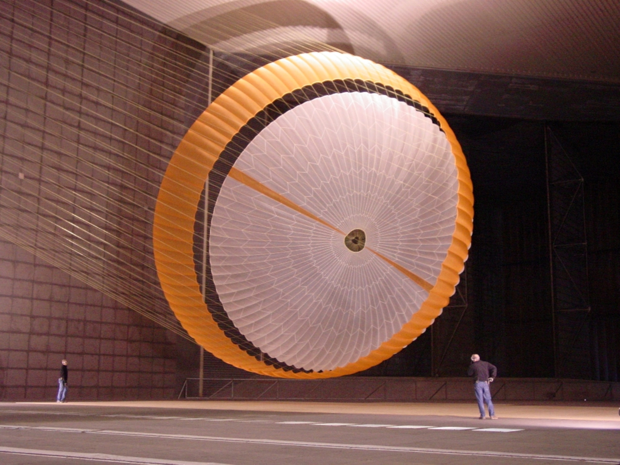 In AEDC’s National Full-Scale Aerodynamics Complex, two engineers are dwarfed by NASA's Mars Science Laboratory's parachute. The parachute holds more air than a 3,000-square-foot house and is designed to survive loads in excess of 36,000 kilograms (80,000 pounds). The parachute is attached to a launch arm mounted on a swivel-base that allows the test item to pitch and yaw under simulated conditions of subsonic entry into the Martian atmosphere. (Photo courtesy of NASA/JPL and Pioneer Aerospace Corp.)