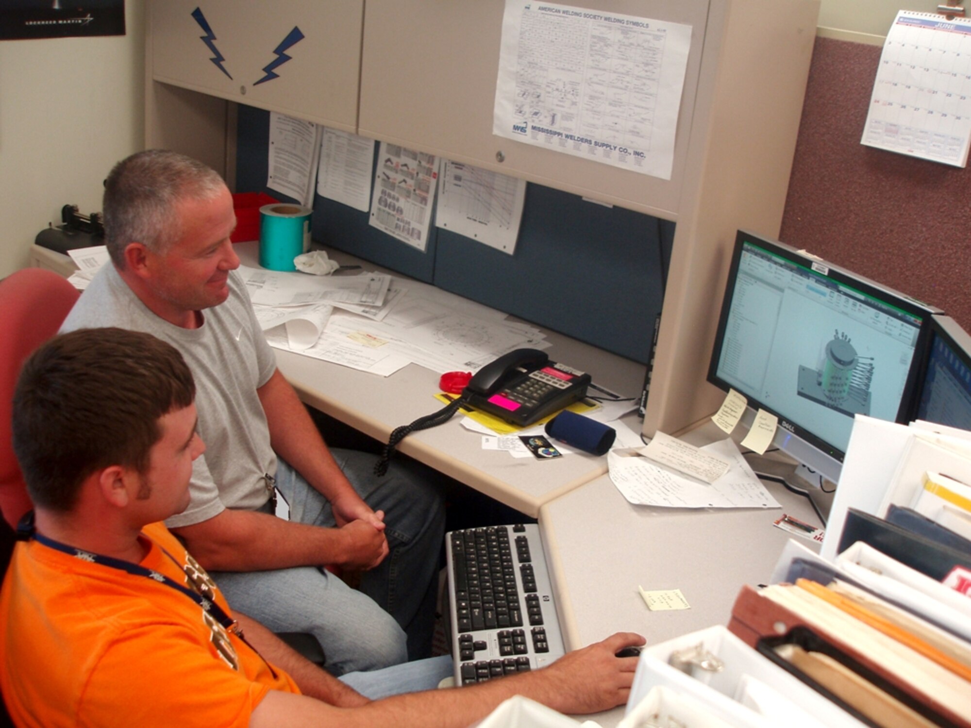 Kevin Thompson, HTL lead engineer,left, and Nathan Lister, HTL test engineer, review Lister’s design that will result in a cost savings of $25,500. (Photo by Consetta Woosley)