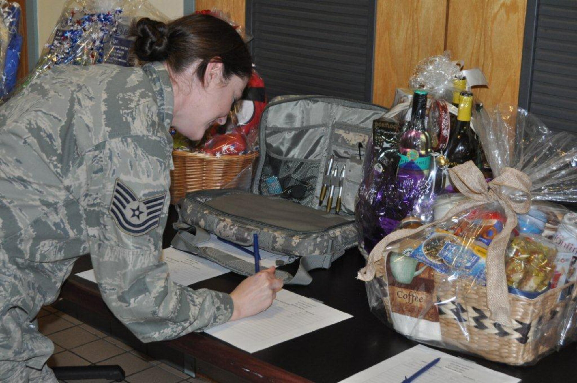 Tech. Sgt. Shelly Toney, 916th Force Support Squadron, places a bid on one of the several baskets auctioned off in order to raise funds for the 2012 Family Day celebration. (USAF photo by Maj. Erin Karl, 916ARW/PA)