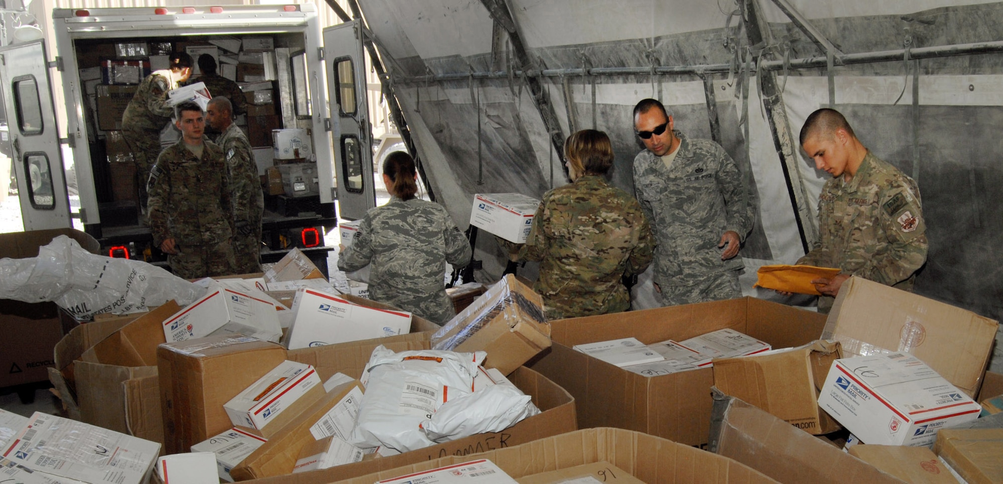 U.S. Air Force Airmen assigned to the 451st Air Expeditionary Wing here, sort through pallets of packages destined for deployed Airmen. The Kandahar Airfield post mail center sorts packages by wings, battalions and the various coalition forces and contractors deployed to KAF. (U.S. Air Force photo/Master Sgt. James Martin/RELEASED