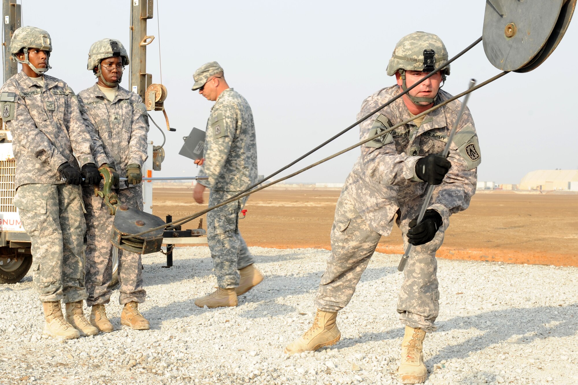 SOUTHWEST ASIA - U.S. Army Staff Sgt. Howard Clifford, safety NCO in charge crew chief, ensures the cable on the crane of a guided missile transporter is not tangled  as Pfc. Tiffany Sanchez and Sgt. Shantelle Campbell, missile reload crew members, hold it taught during a missile reload certification Aug. 4, 2012. The five-solider missile reload team, from the 1st Battalion, 7th Air Defense Artillery Regiment, must reload a heavy expandable mobile tactical truck with four new canisters within an hour to be considered proficient.  (U.S. Air Force photo/Master Sgt. Scott MacKay)