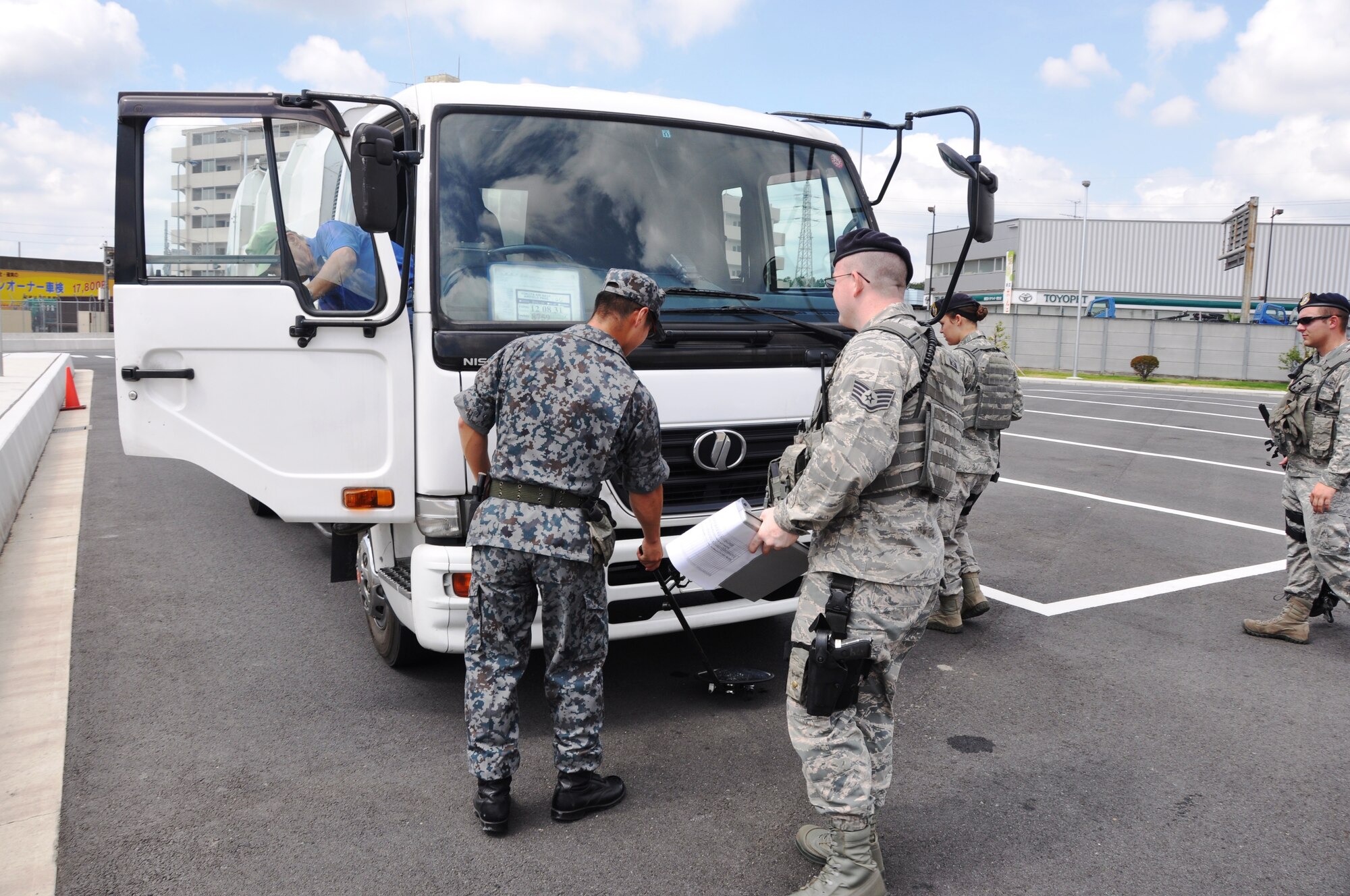 YOKOTA AIR BASE, Japan -- Members of the 374th Security Forces Squadron and Air Defense Command work together to perform a vehicle inspection outside the supply gate Aug. 2, 2012 at Yokota Air Base, Japan. Every day, Security Forces Airmen work hand-in-hand with members of the ADC to help foster a stronger relationship with the local community. (U.S. Air Force photo by Senior Airman Katrina R. Menchaca)