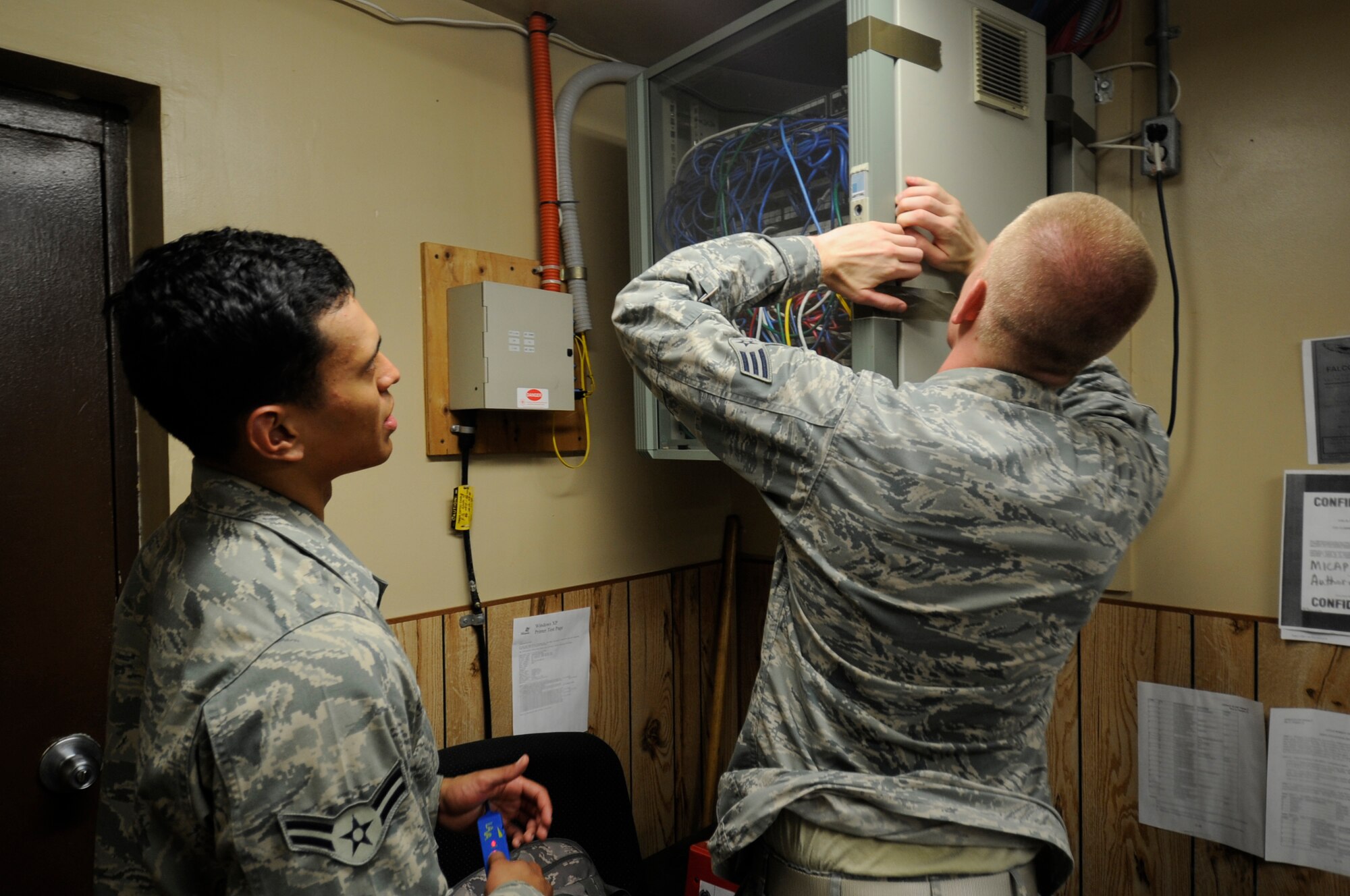 Airman 1st Class Joseph Pandolfo, left, 8th Communications Squadron client systems technician, waits for Senior Airman Joshua McMaster, right, 8th CS CST, to open a switch box, July 26, 2012, on Kunsan Air Base, Republic of Korea. The switch routes internet to all networked computers in the building, which CSTs use to trace connections back and forth. (U.S. Air Force photo/Senior Airman Jessica Hines) 