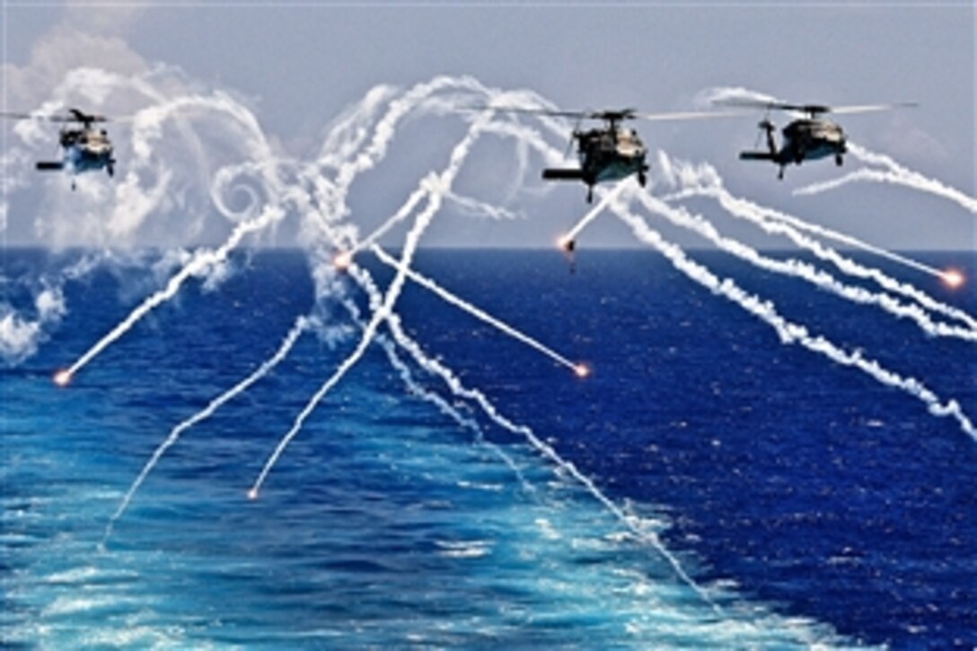 MH-60S Seahawk helicopters fire flares as they approach the aircraft carrier USS Abraham Lincoln under way in the Atlantic Ocean, Aug. 2, 2012. 