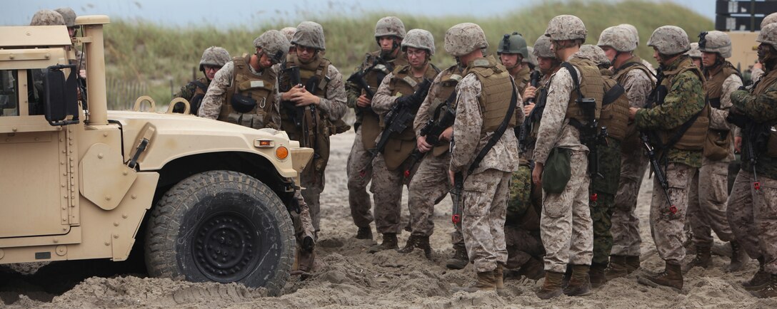 Troops with Combat Logistics Battalion 8, 2nd Marine Logistics Group observe as Cpl. Justin P. Glover, a wrecker operator with the battalion, demonstrates how to attach a chain to a Humvee during a field training exercise aboard Camp Lejeune, N.C., July 31, 2012.  The troops trained in many ways to improve their skills and confidence operating the vehicles in different terrains.  The week-long exercise was designed to prepare the troops for their upcoming deployment to Afghanistan.  