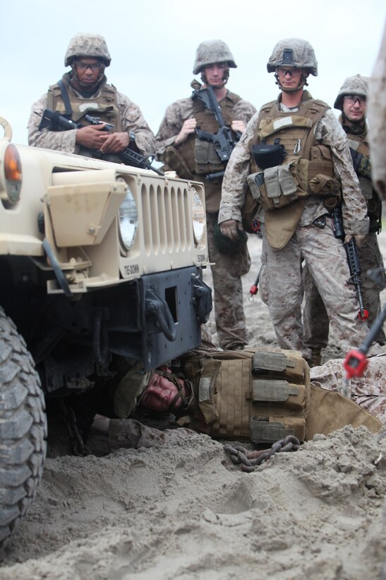 Cpl. Justin P. Glover, a wrecker operator with Combat Logistics Battalion 8, 2nd Marine Logistics Group, shows fellow troops how to attach a chain to a Humvee during a field training exercise aboard Camp Lejeune, N.C., July 31, 2012. The troops trained in many ways to improve their skills and confidence operating the vehicles in different terrains.  The week-long exercise was designed to prepare the troops for their upcoming deployment to Afghanistan.  