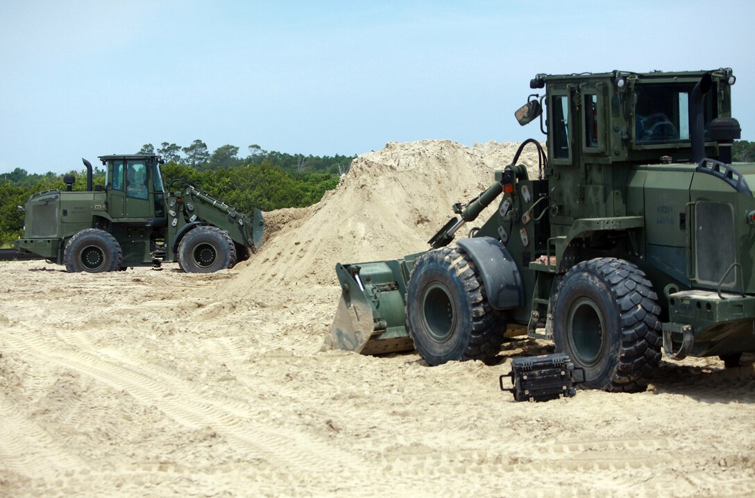 A multi-purpose tractor lifts dirt during a training exercise with 8th Engineer Support Battalion, 2nd Marine Logistics Group at Onslow Beach aboard Camp Lejeune, N.C., July 25, 2012. Along with conducting training to refresh their own skills, 8th ESB was joined by Marines with 6th ESB, the battalion’s reserve counterpart.  (U.S. Marine Corps photo by Pfc. Franklin E. Mercado)